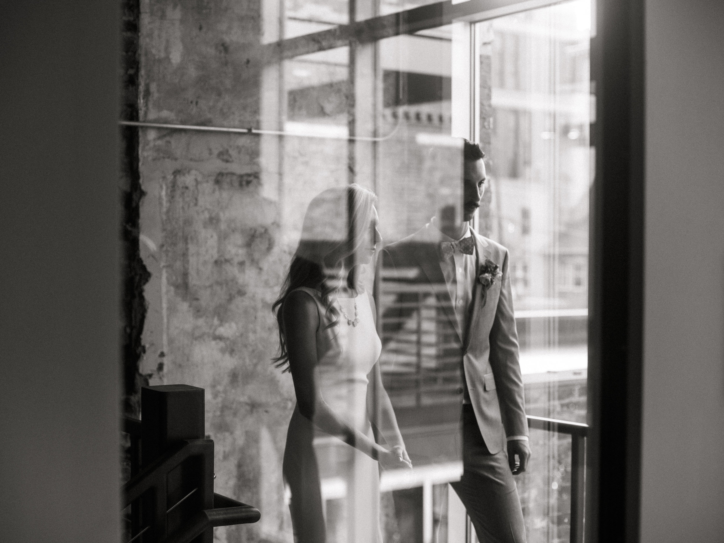 Bride and groom reflected in glass black and white