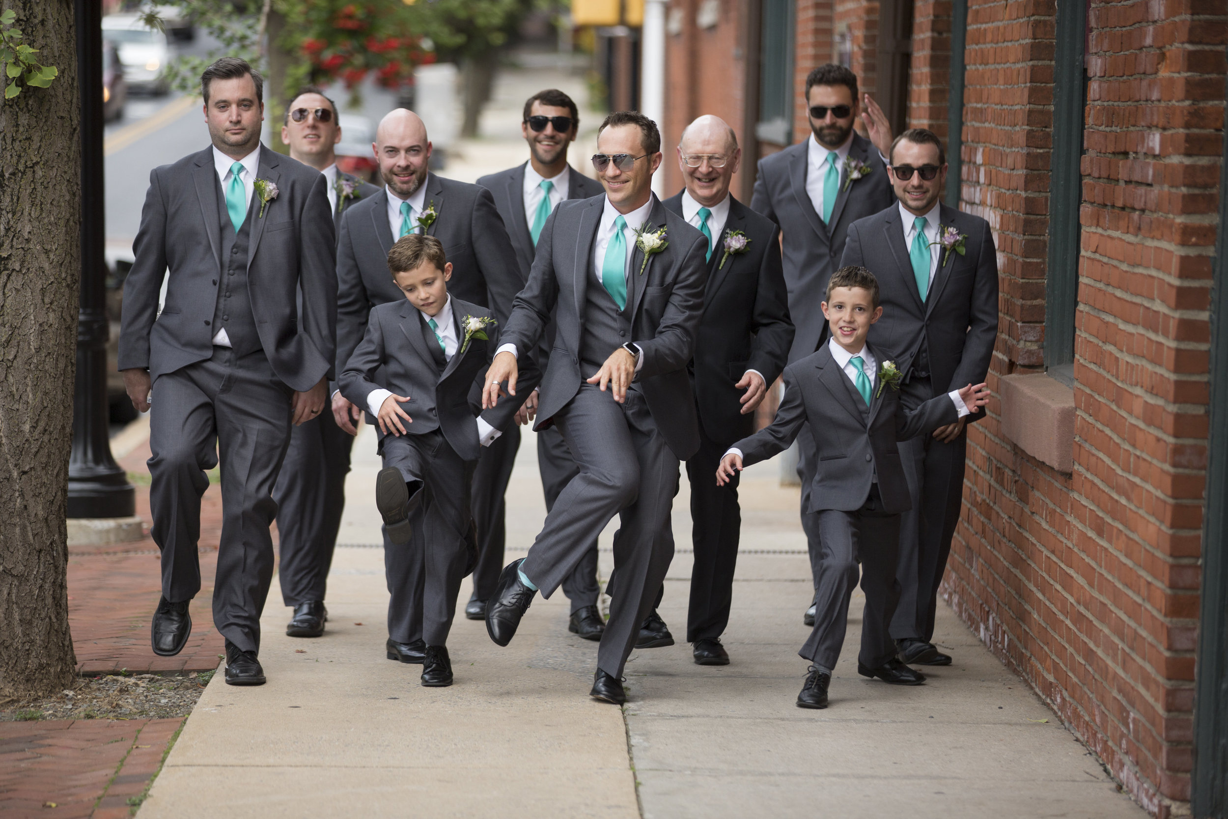 Groom and groomsmen walking and dancing up sidewalk Lancaster city