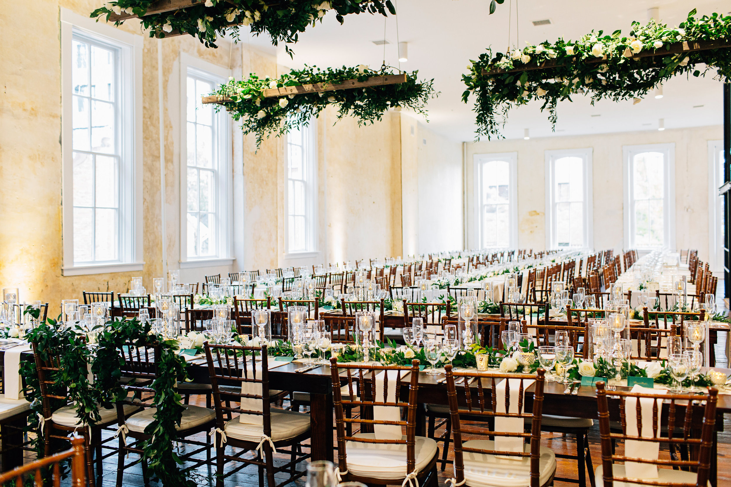 Wedding reception dinner tables with hanging greenery