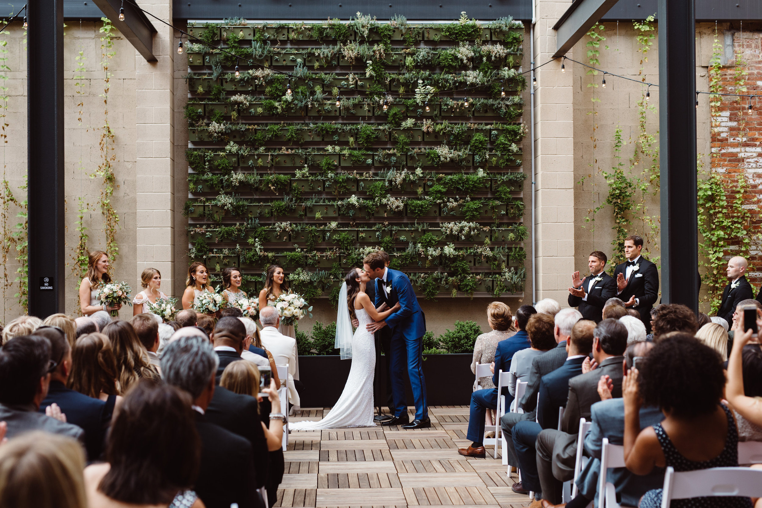 First kiss in front of the green succulent wall in the Terrace at Excelsior wedding venue