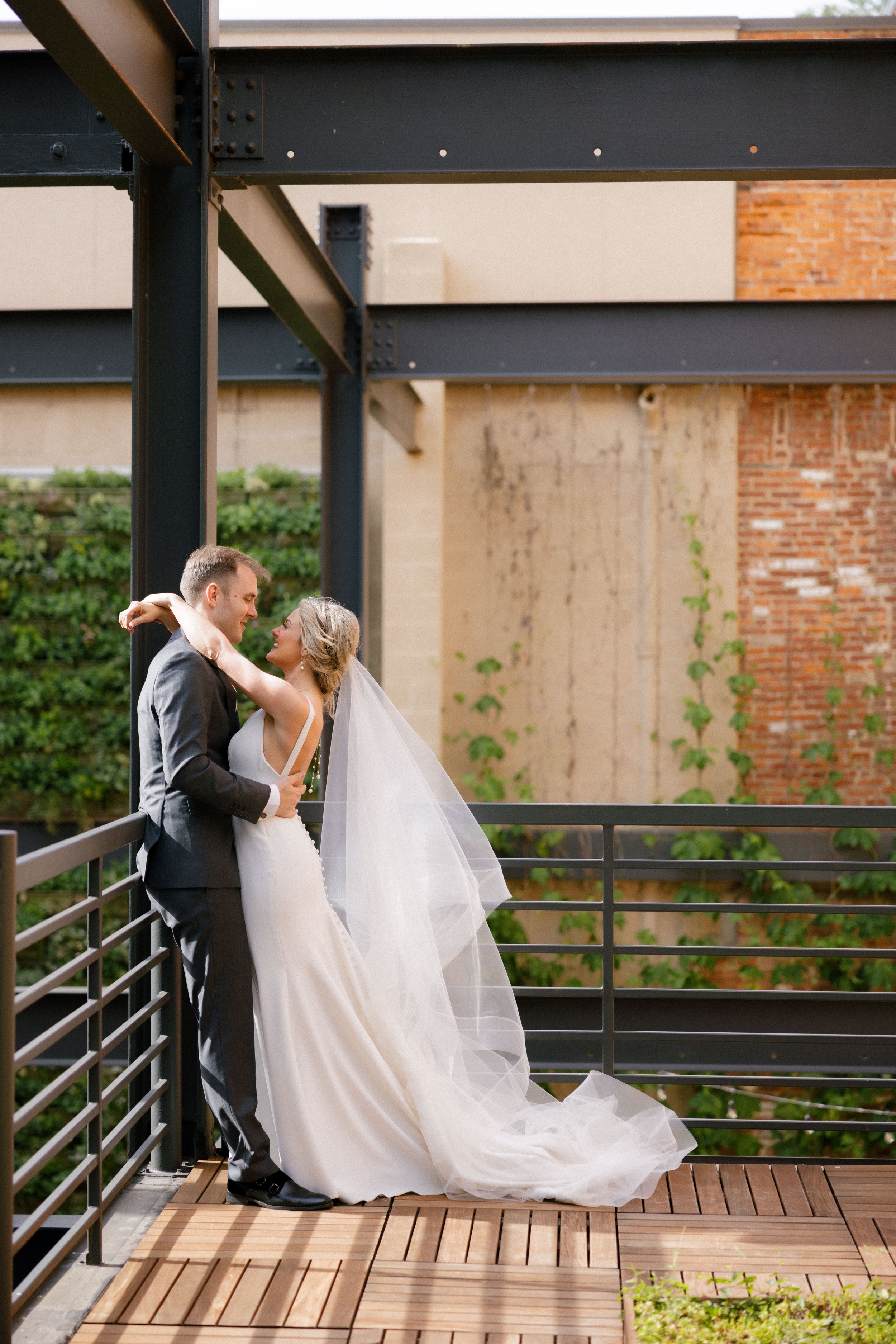 Bride and groom on rooftop deck patio overlooking green wall