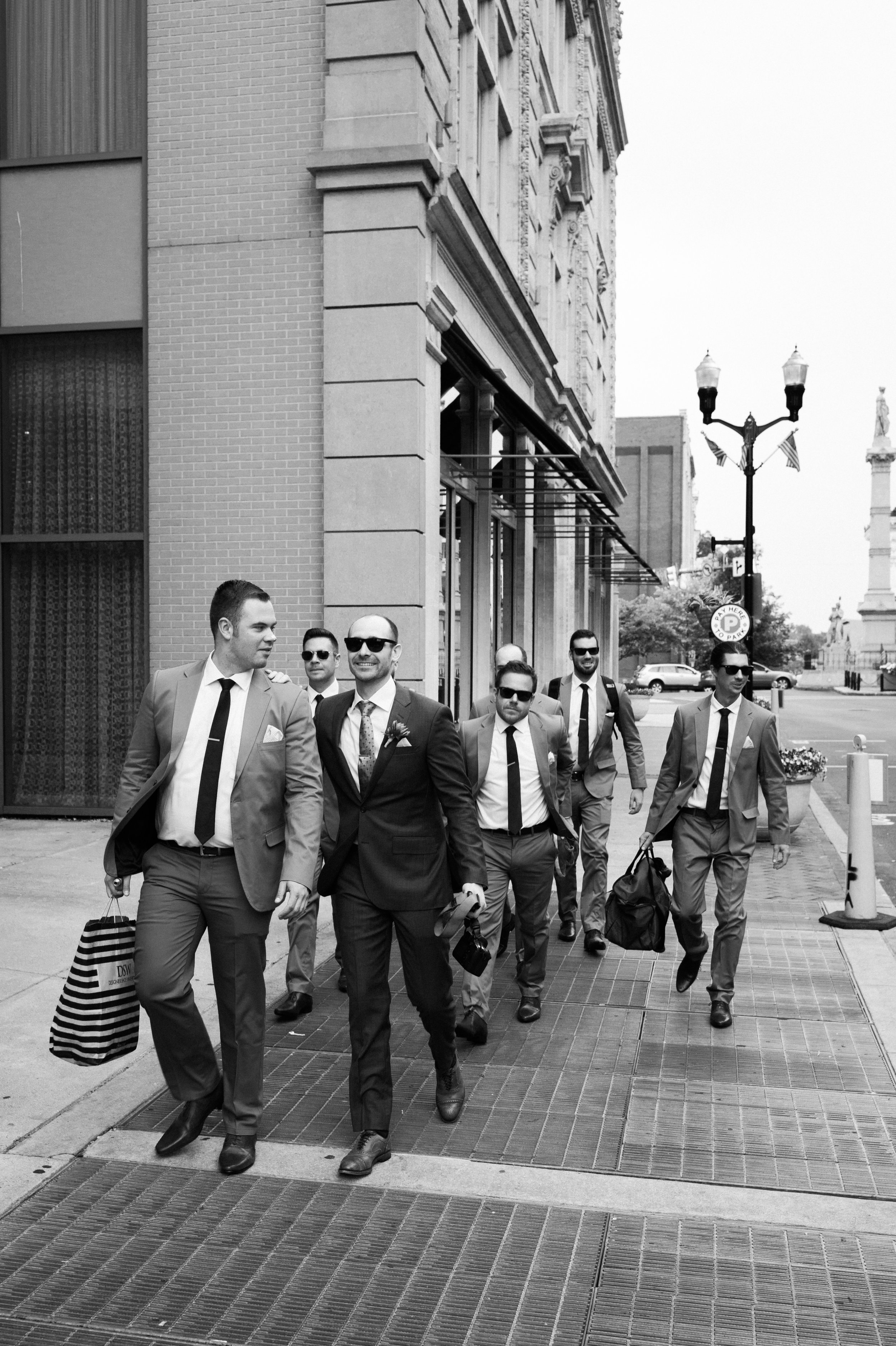 Groom and groomsmen walking down sidewalk