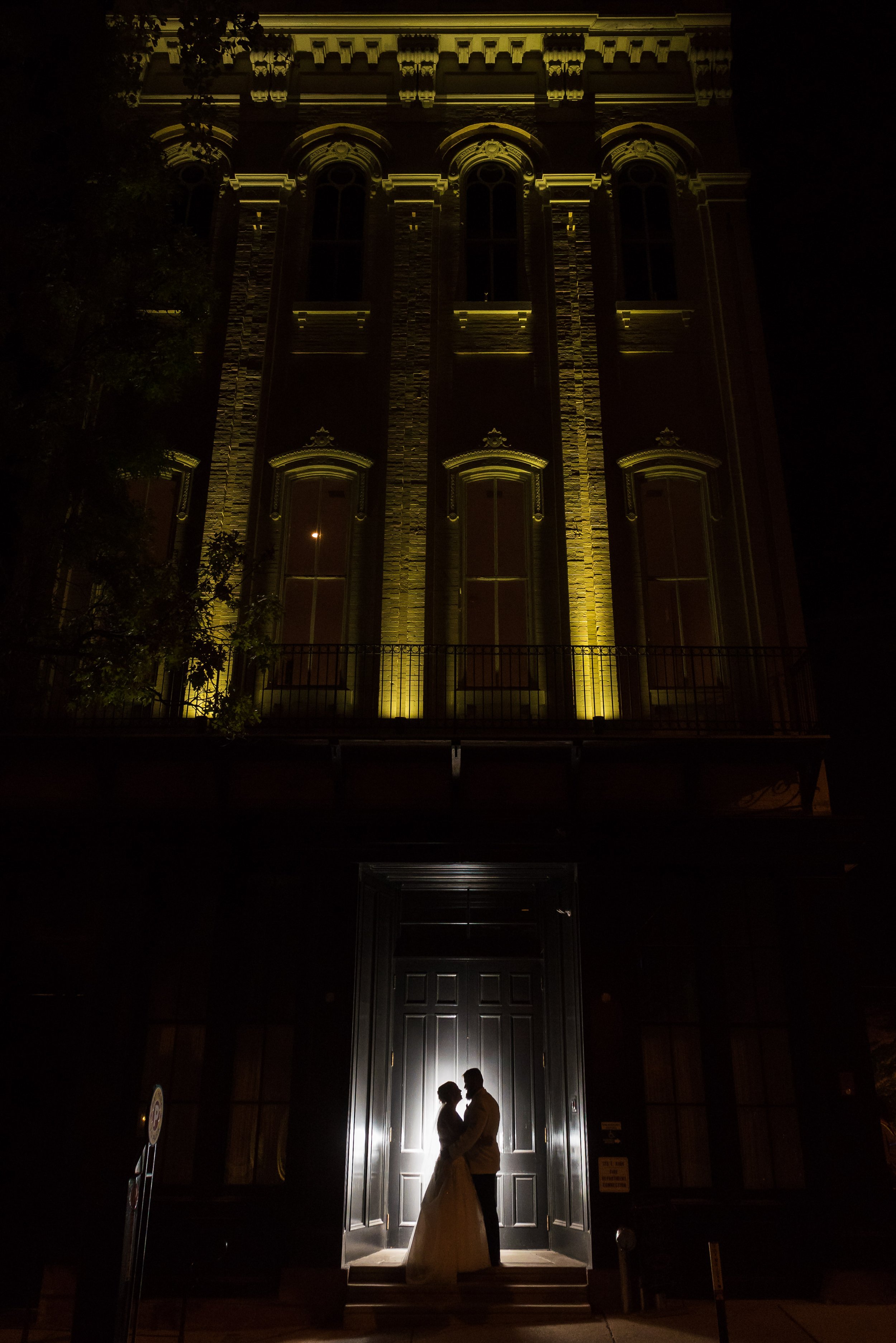 Bride and groom dramatically lit up against dark Excelsior facade