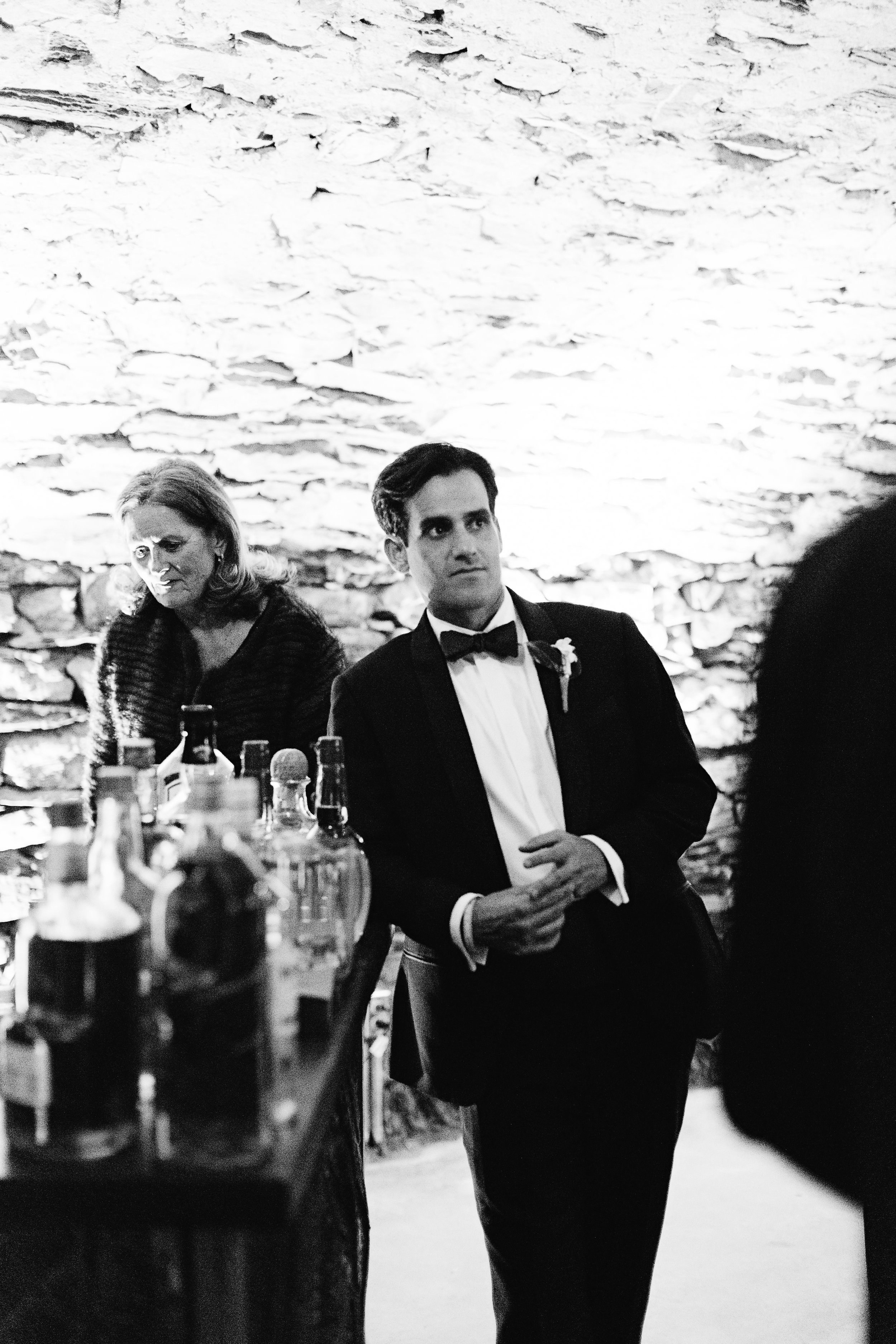 Groom leaning against the bar in dramatic black and white 
