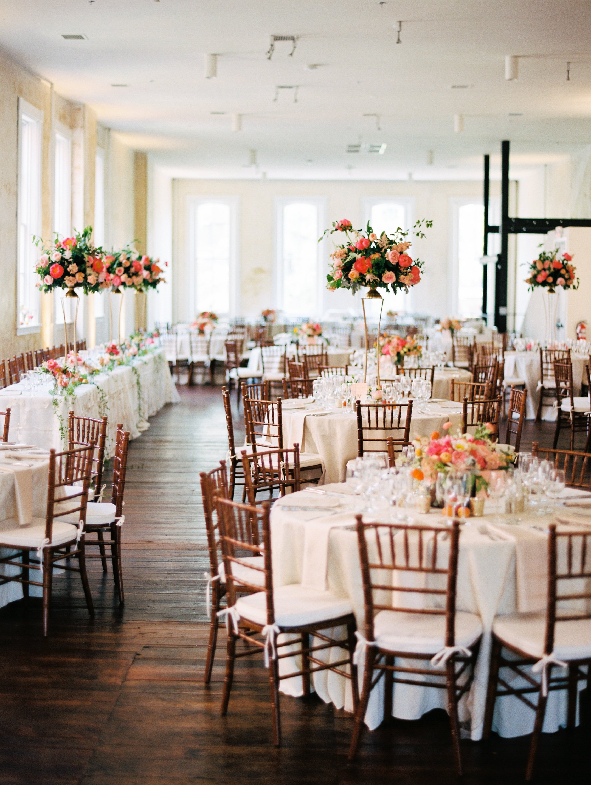 Eclectic and sophisticated wedding reception set up with brown wood chairs and beige linens