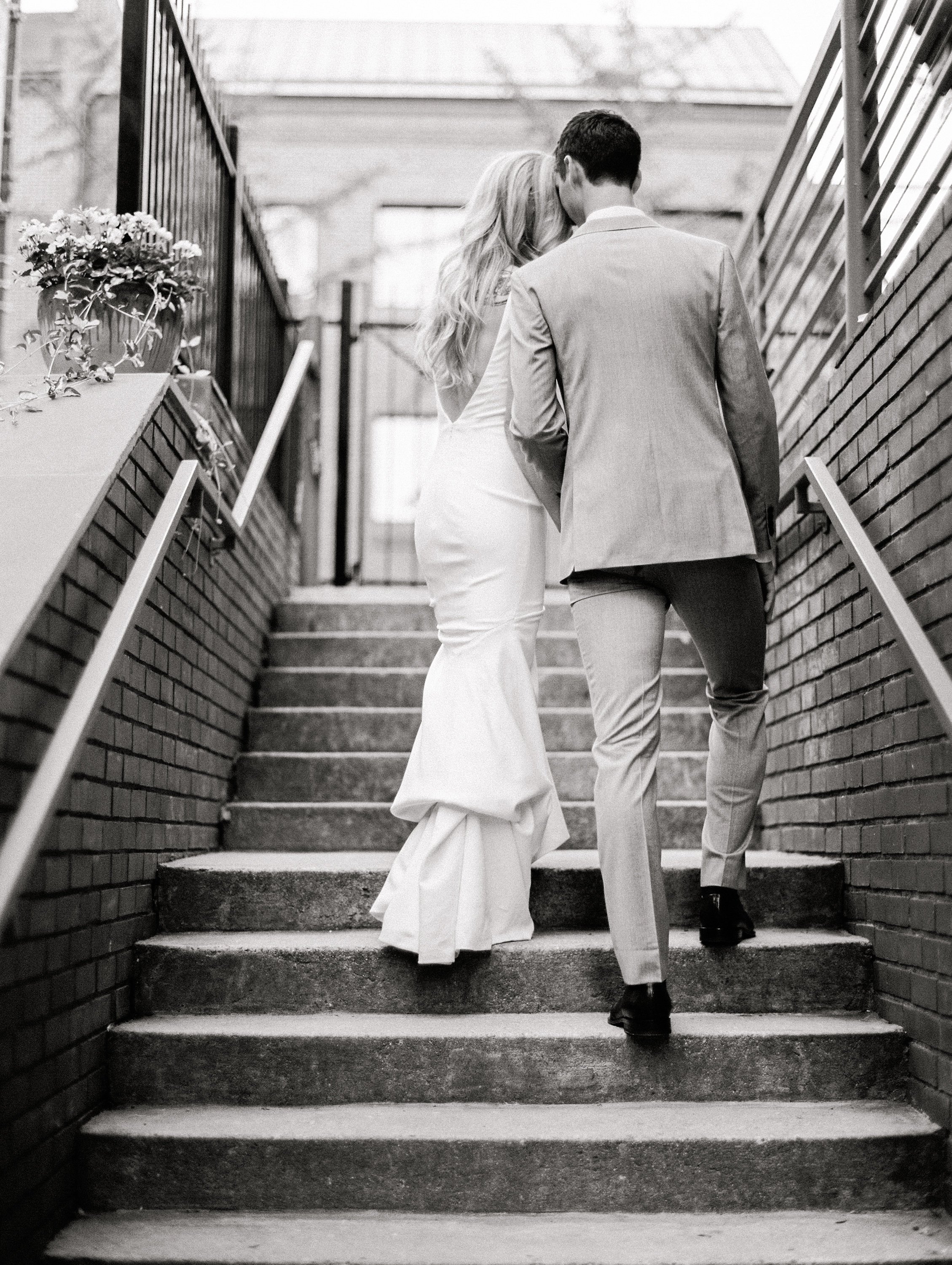 Couple ascending stairs kissing black and white
