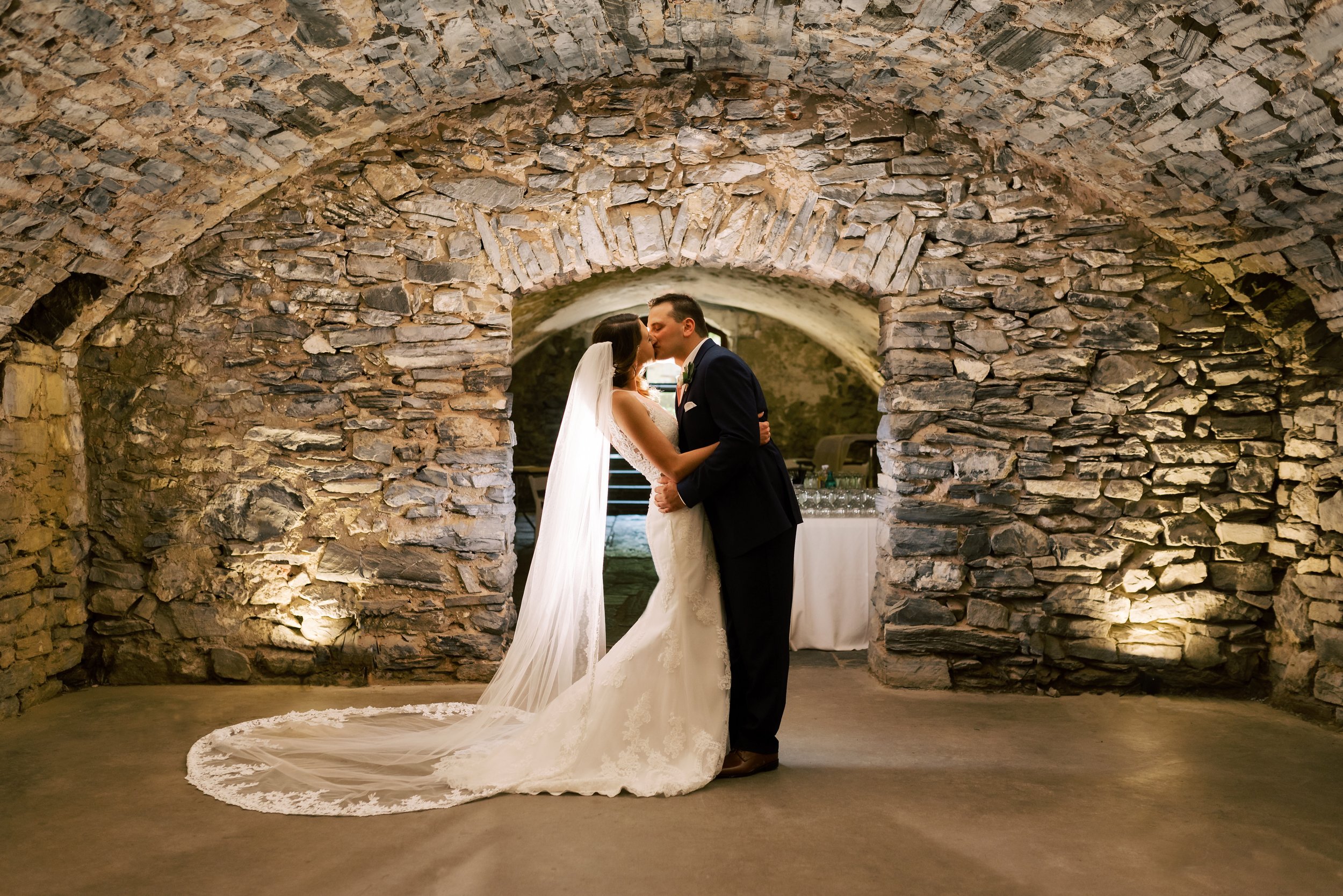 Bride and groom kissing in catacombs dramatic lighting