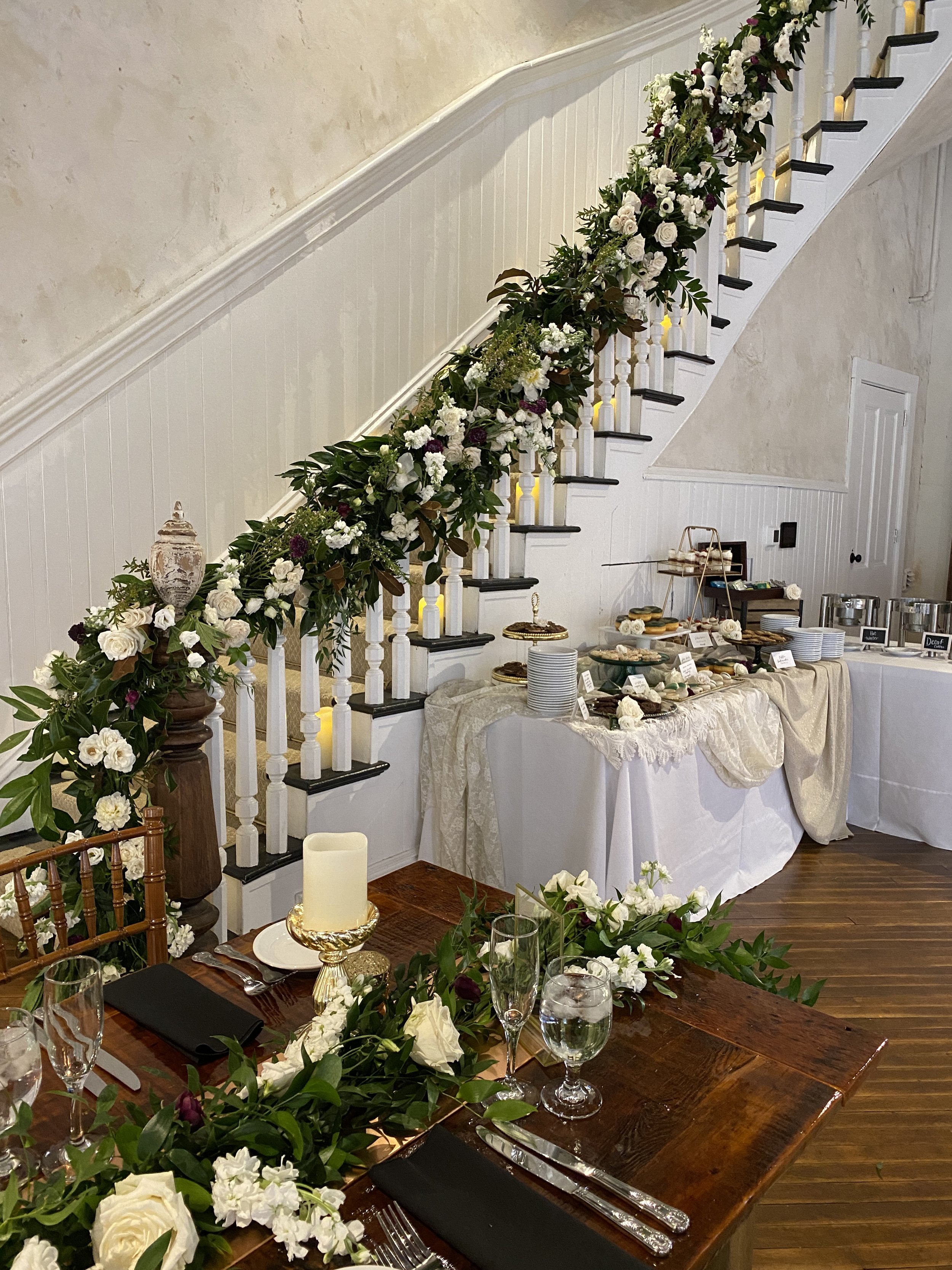 Grand staircase covered in flowers and dessert table