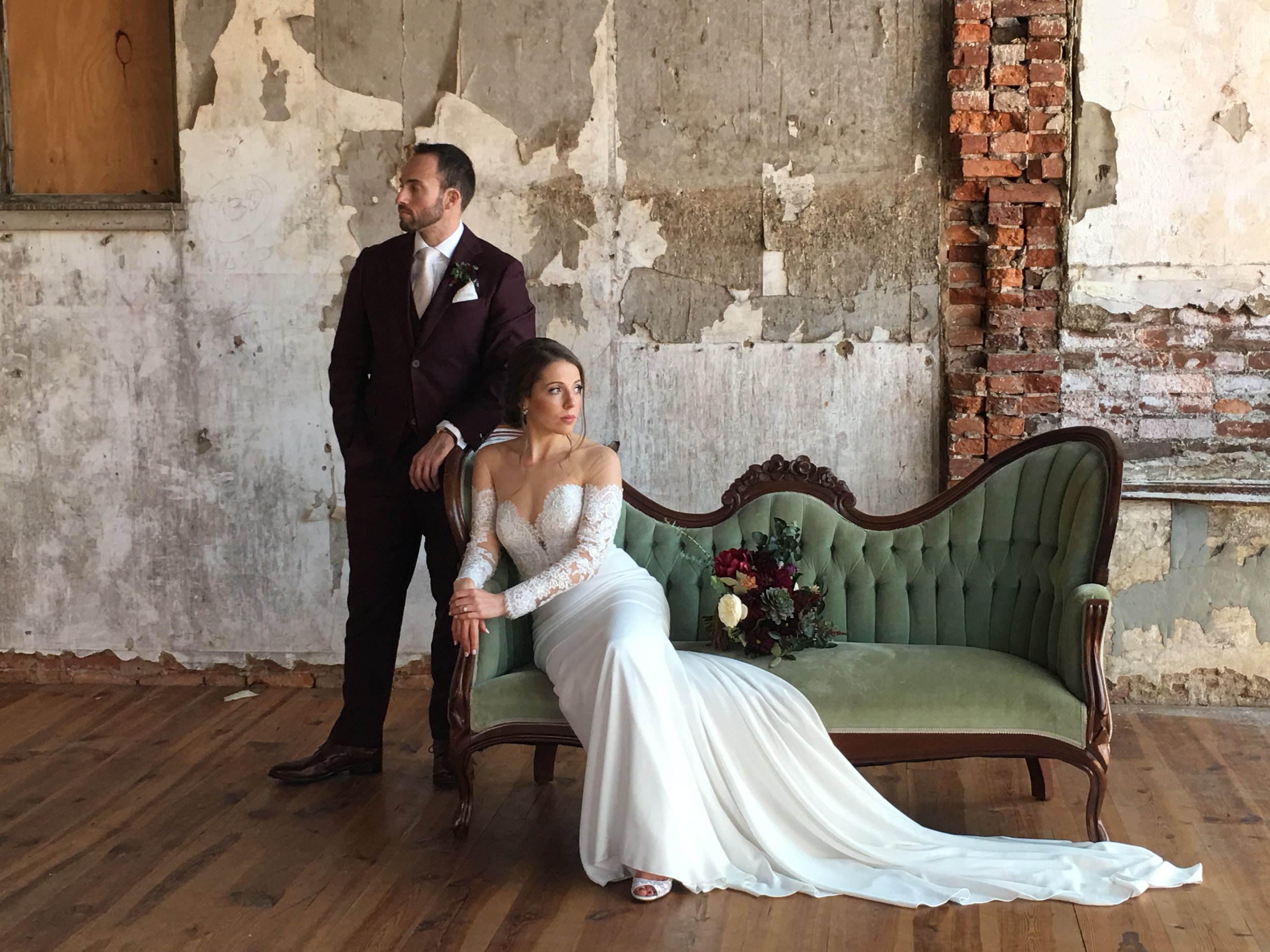 Groom and bride lounging on green loveseat in historic antique room