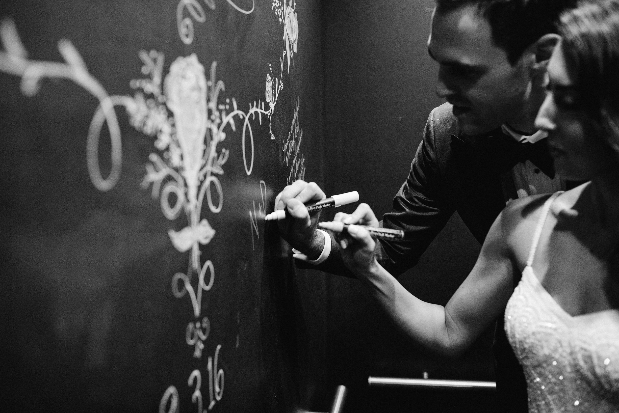 Bride and groom writing on chalkboard wall in elevator at Excelsior Lancaster PA