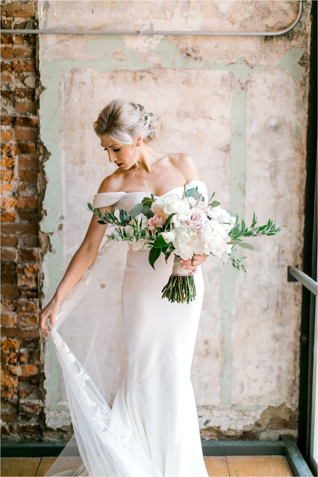 Bride holding dress and large white bouquet