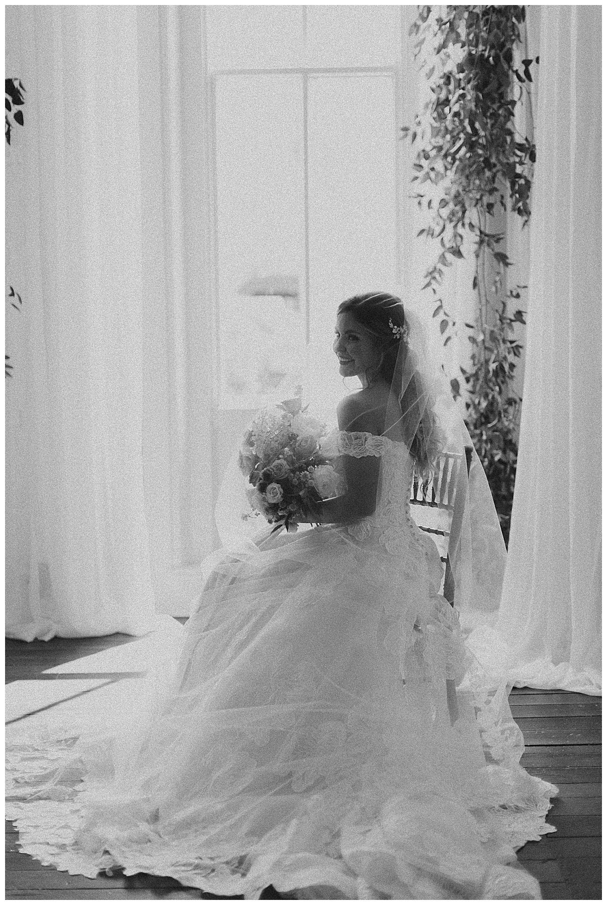 Bride sitting in front of large window black and white