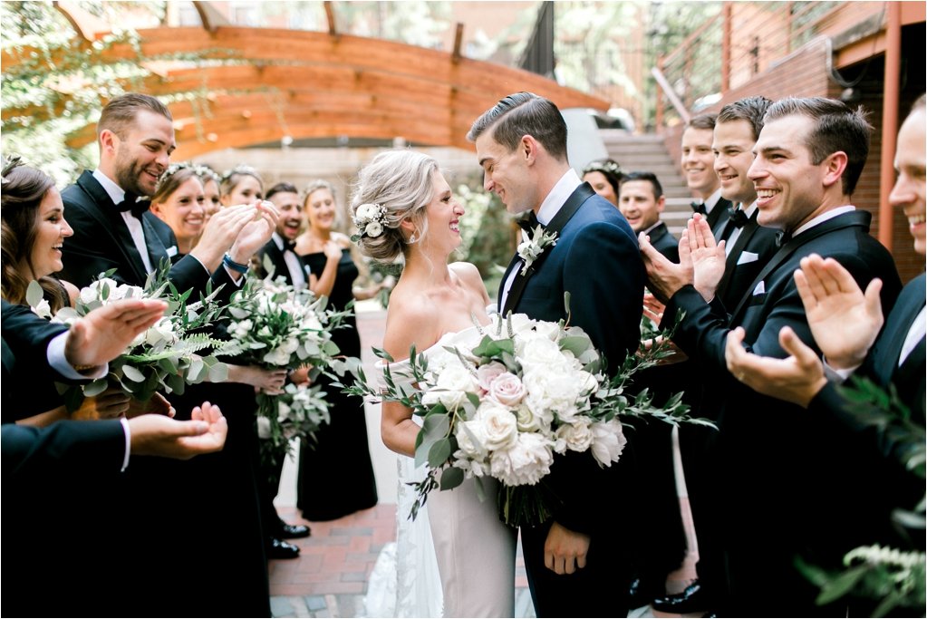 Bride and groom surrounded by bridal party in garden courtyard