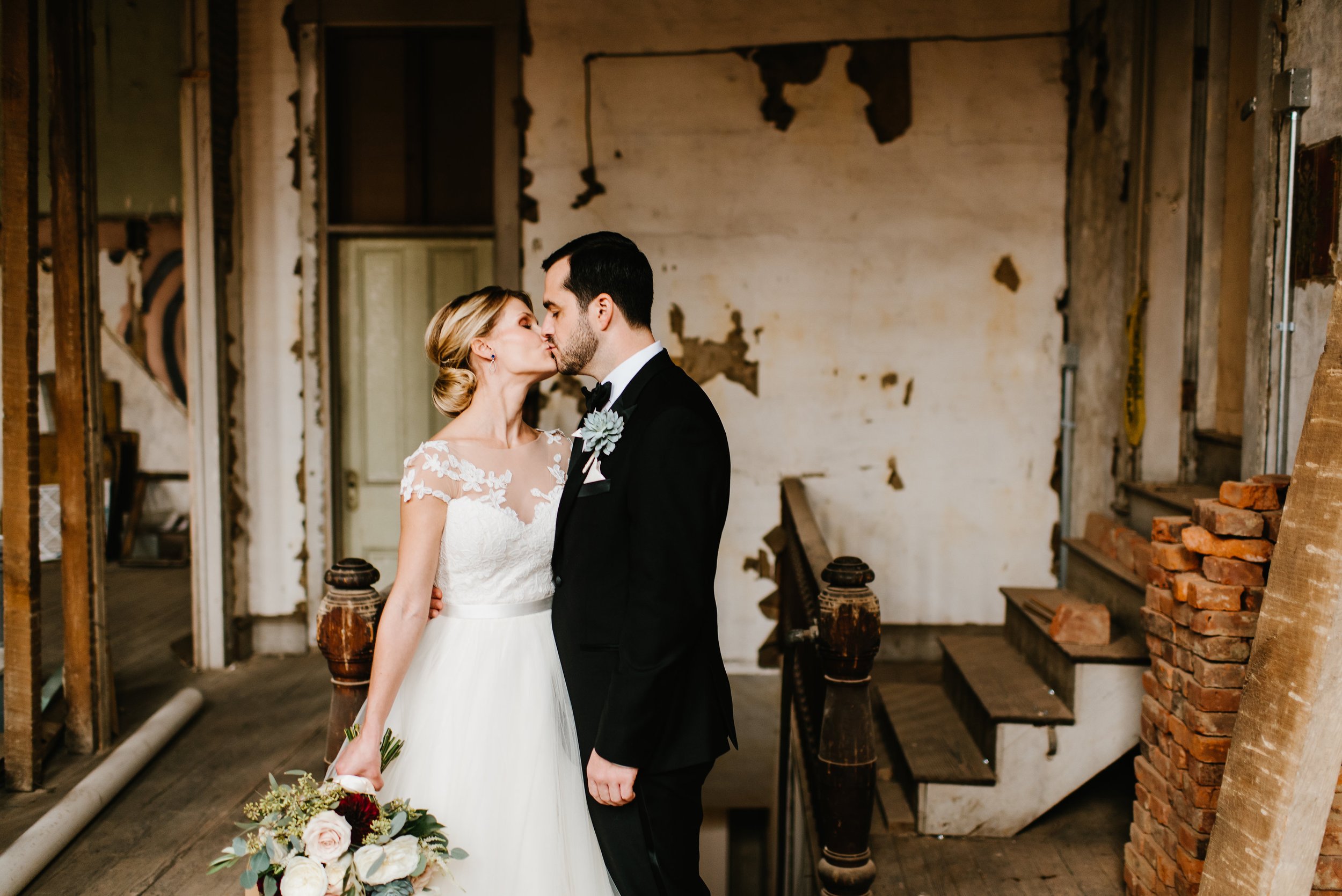 Bride and groom kissing in antique unfinished historic room