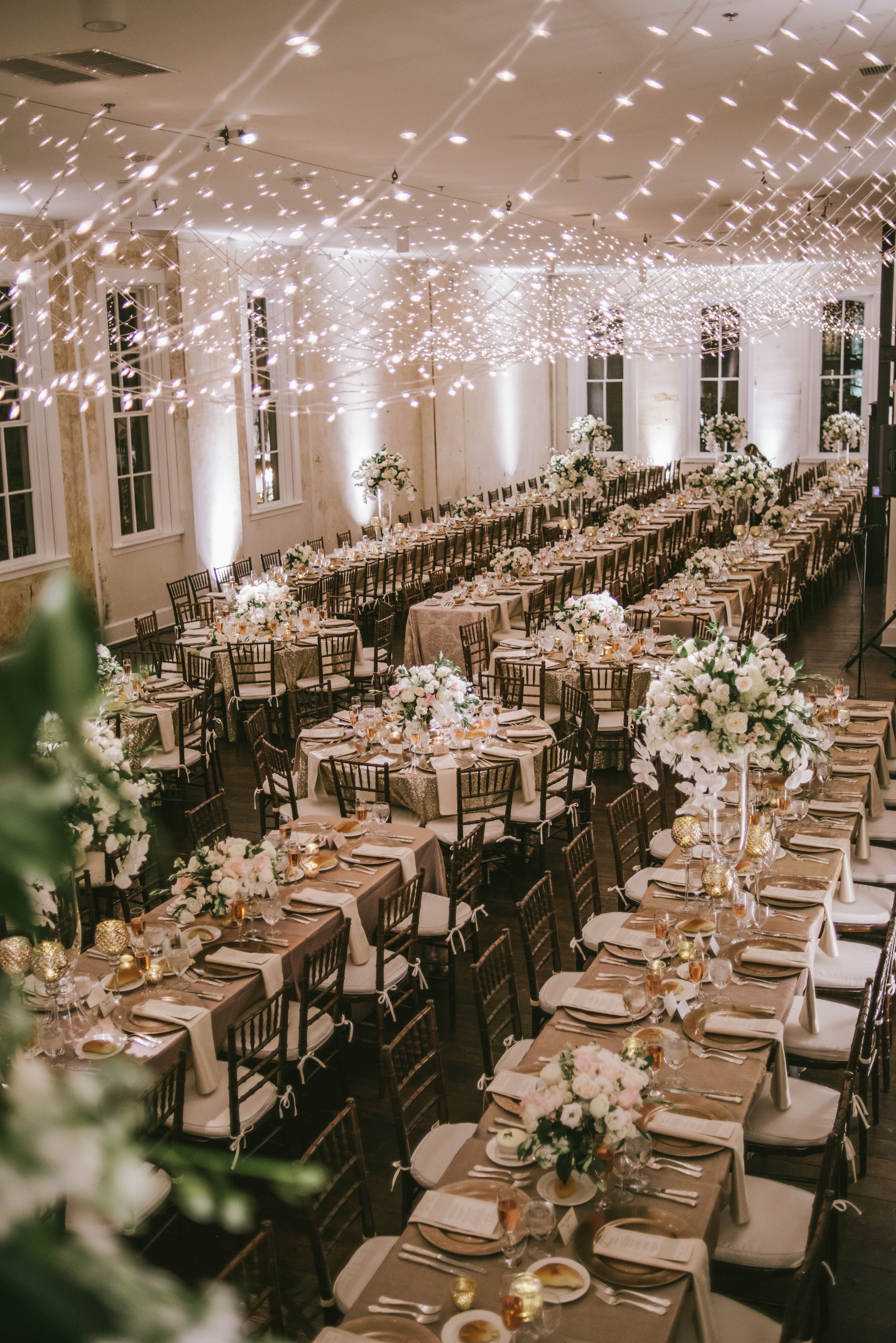 Wedding reception dinner tables with greenery and hanging lights