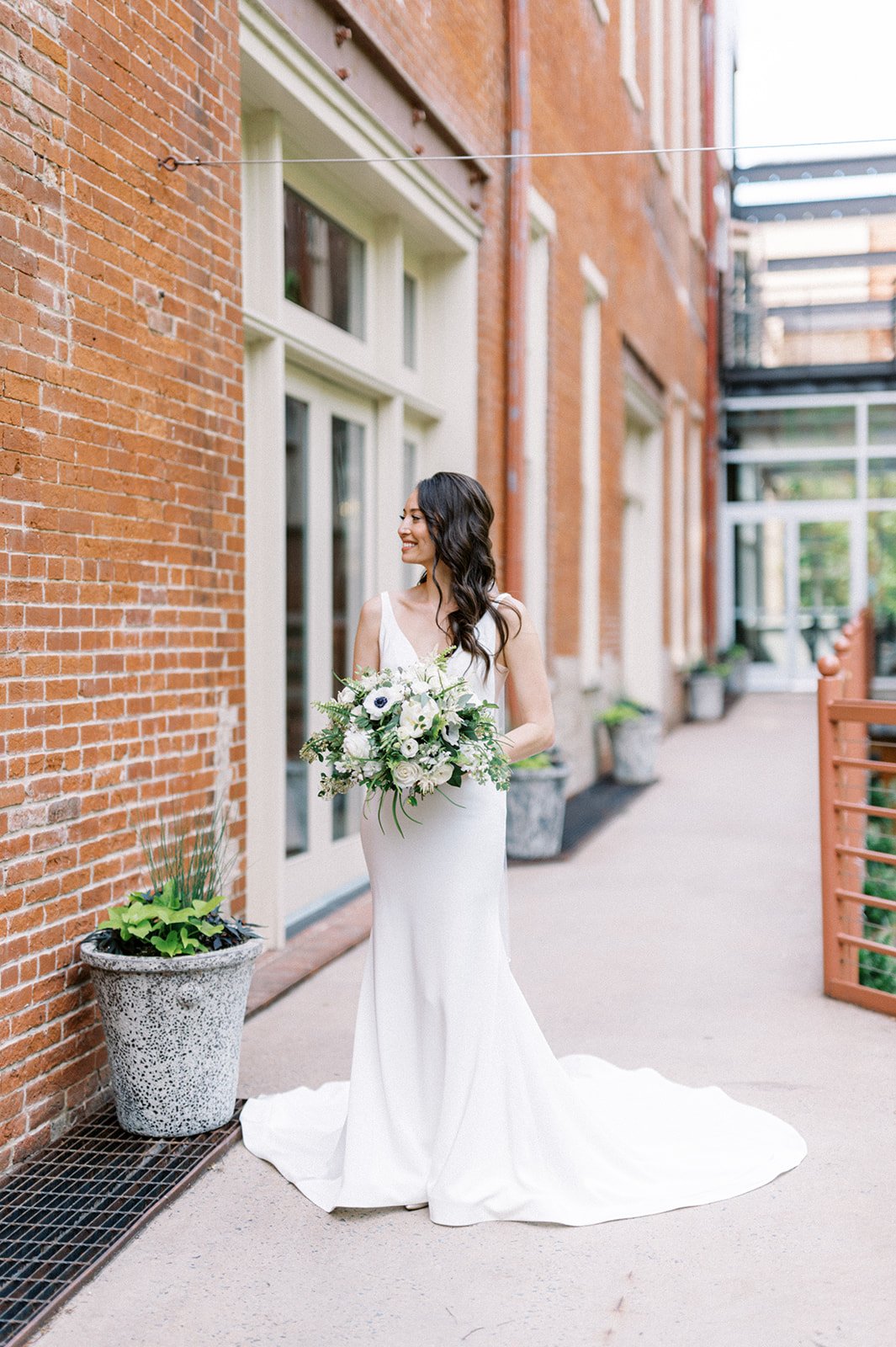 Bride holding bouquet in front of brick wall of Excelsior wedding venue