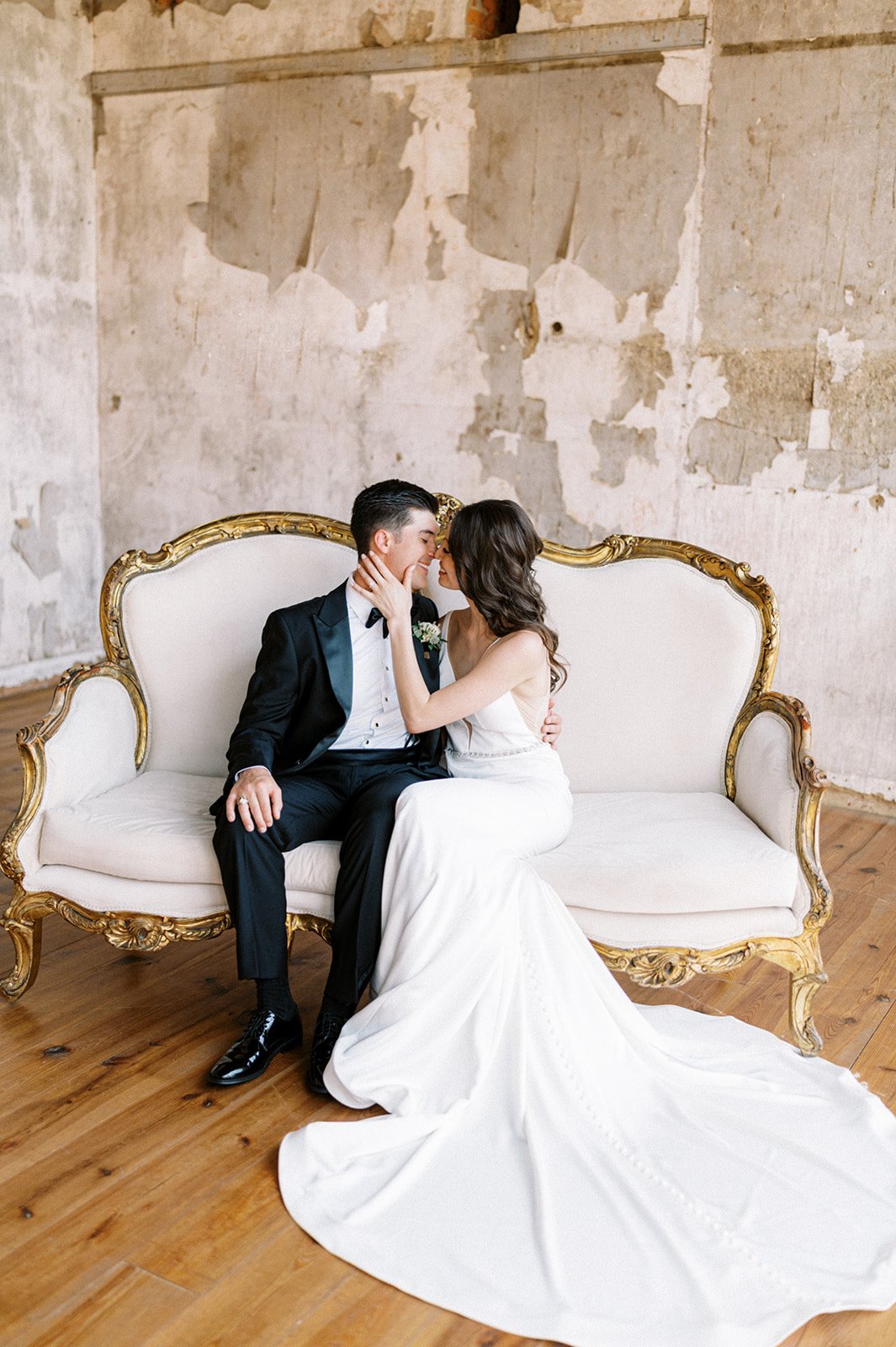 Bride groom kissing on antique vintage loveseat in rustic room