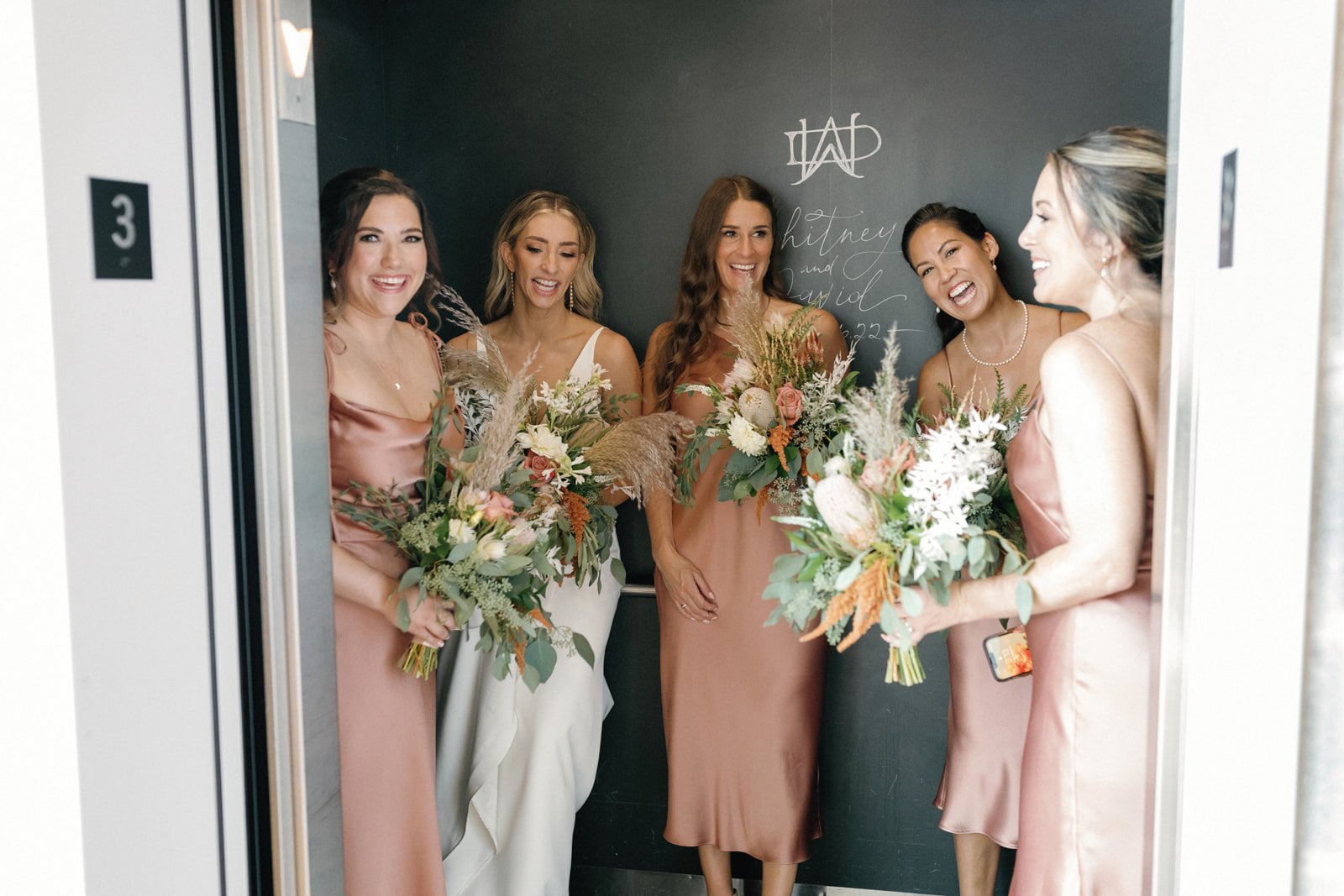 Bridesmaids with bouquets in elevator at Excelsior event venue