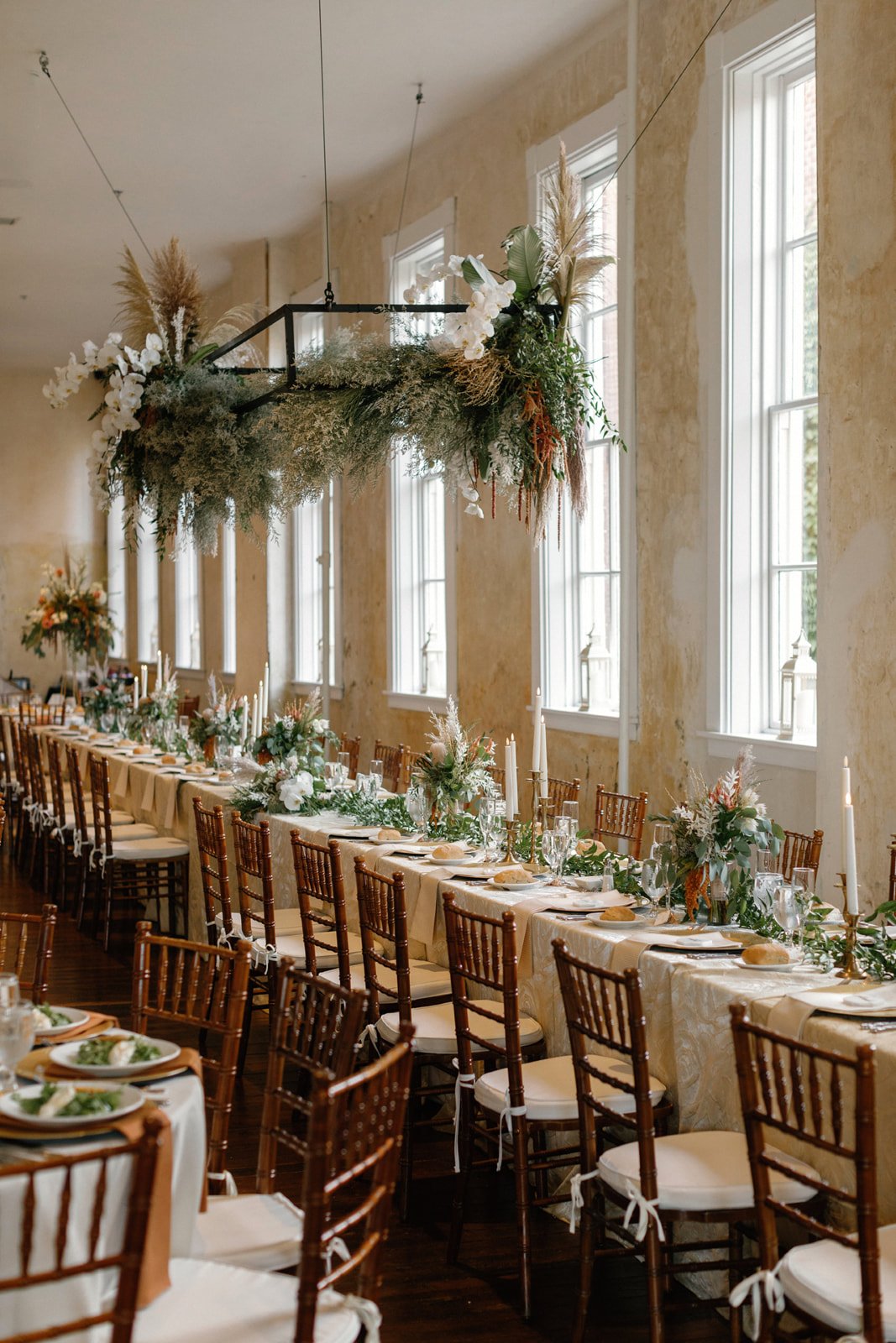 long wedding reception dinner tables with hanging greenery and candles