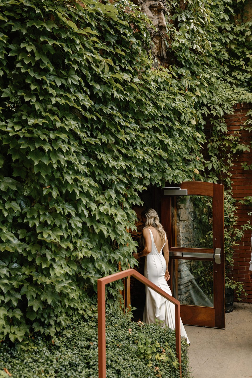 Bride going into catacombs in front of green wall