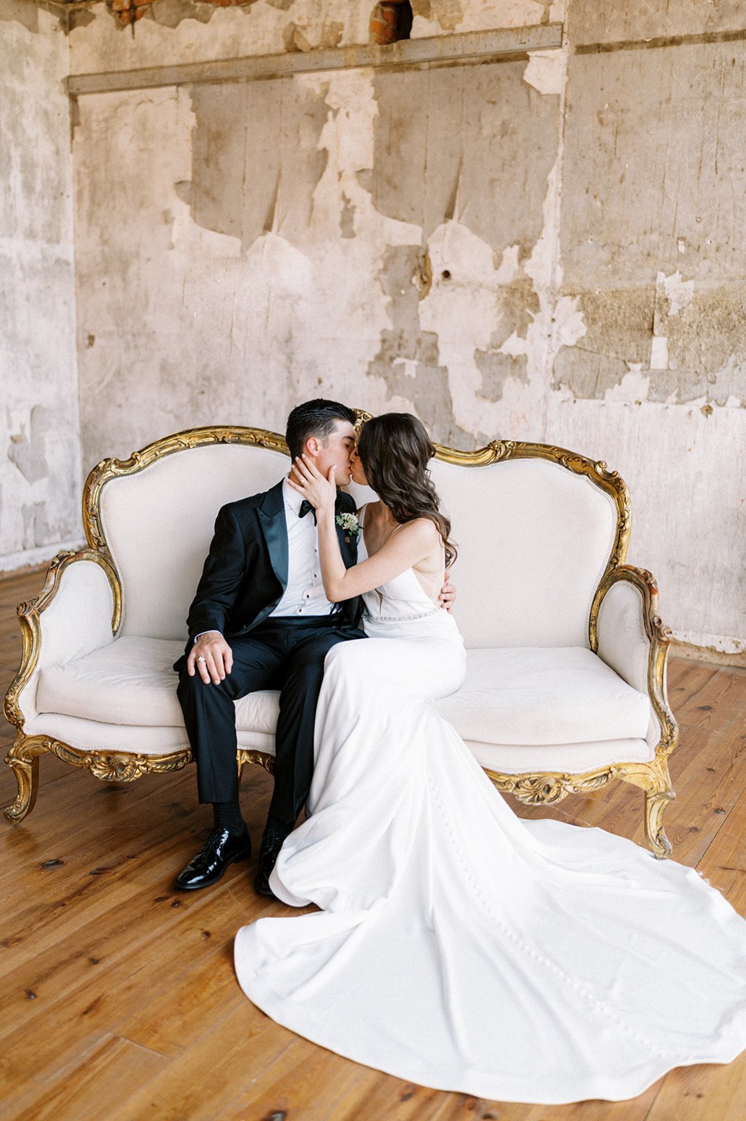 Bride and groom kissing on victorian couch in eclectic room