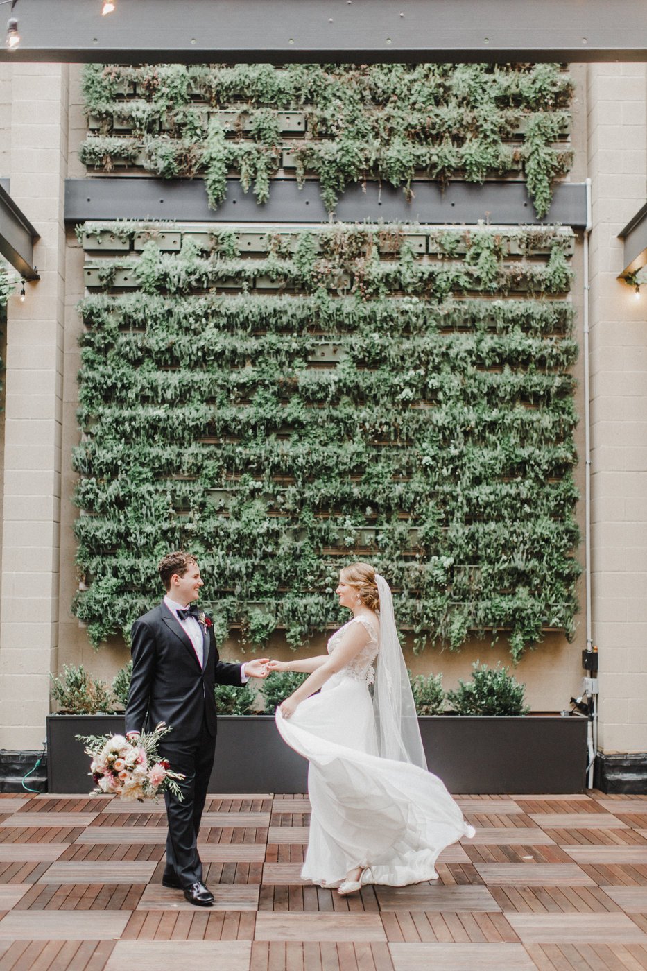 Bride and Groom dancing in front of green succulent wall at Excelsior venue