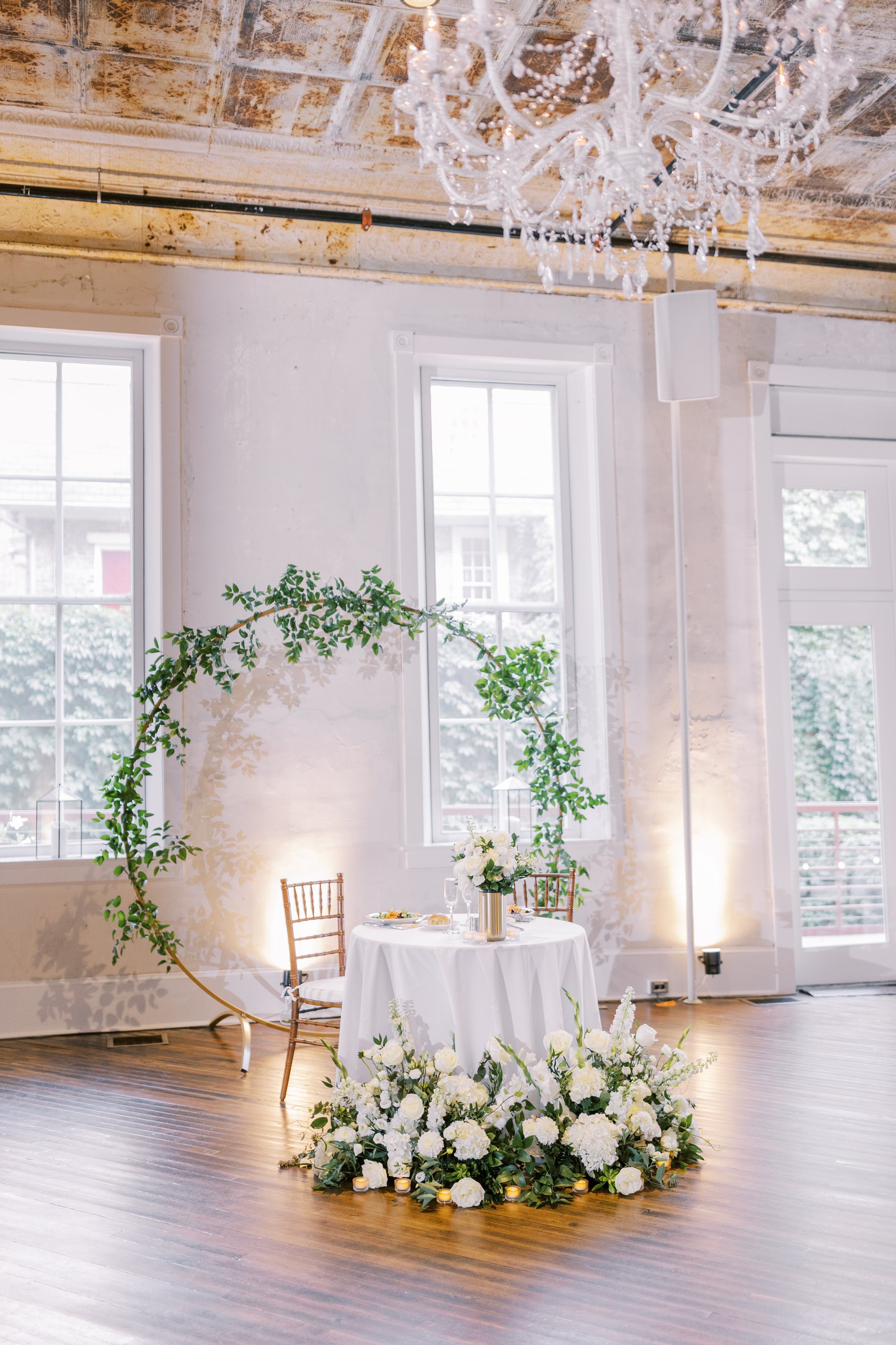 Sweetheart table with piles of roses and large greenery circle display behind