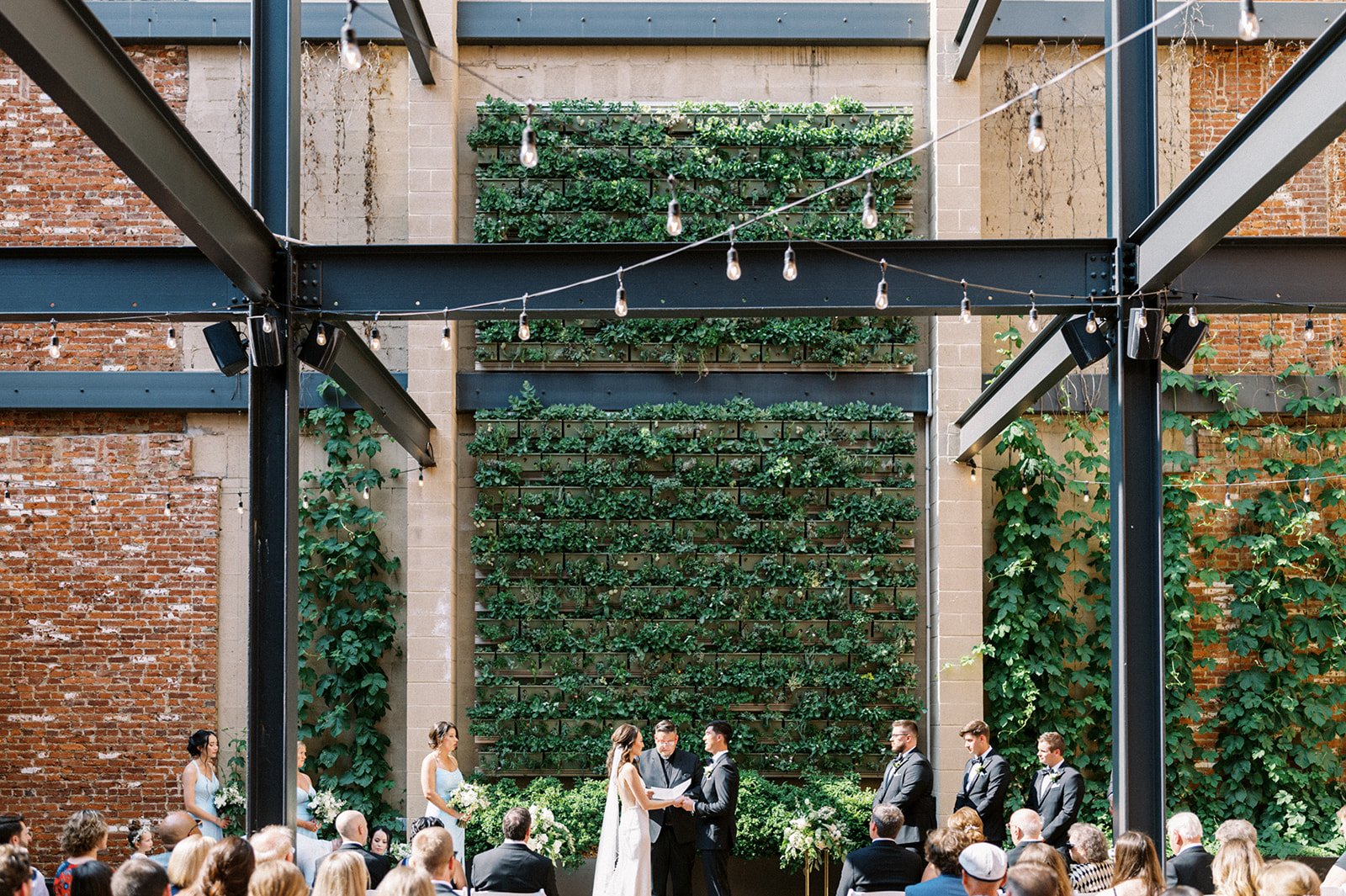 Wedding ceremony taking place in front of green succulent wall