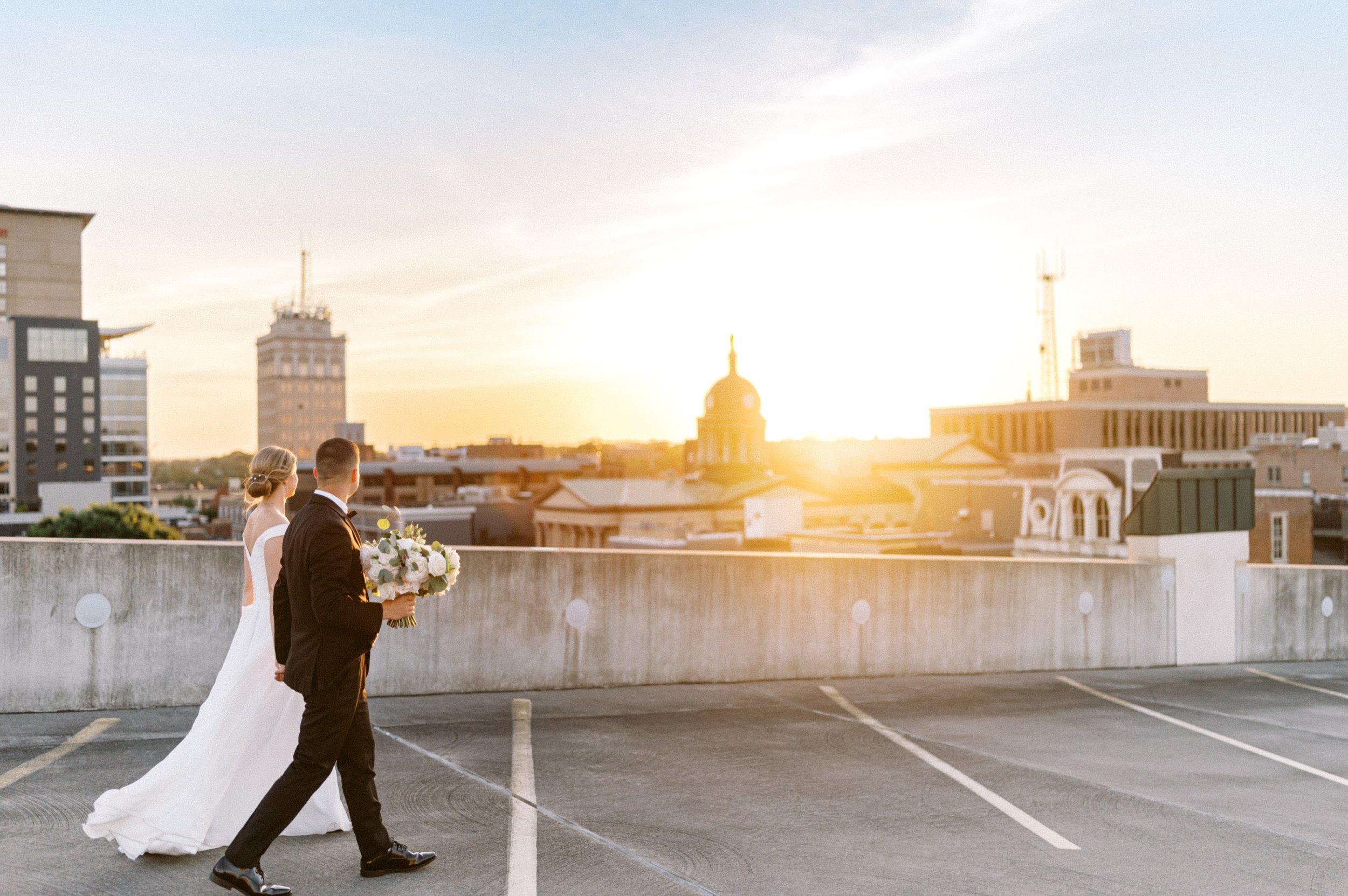 Bride and groom walking rooftop garage Downtown Lancaster with sunset