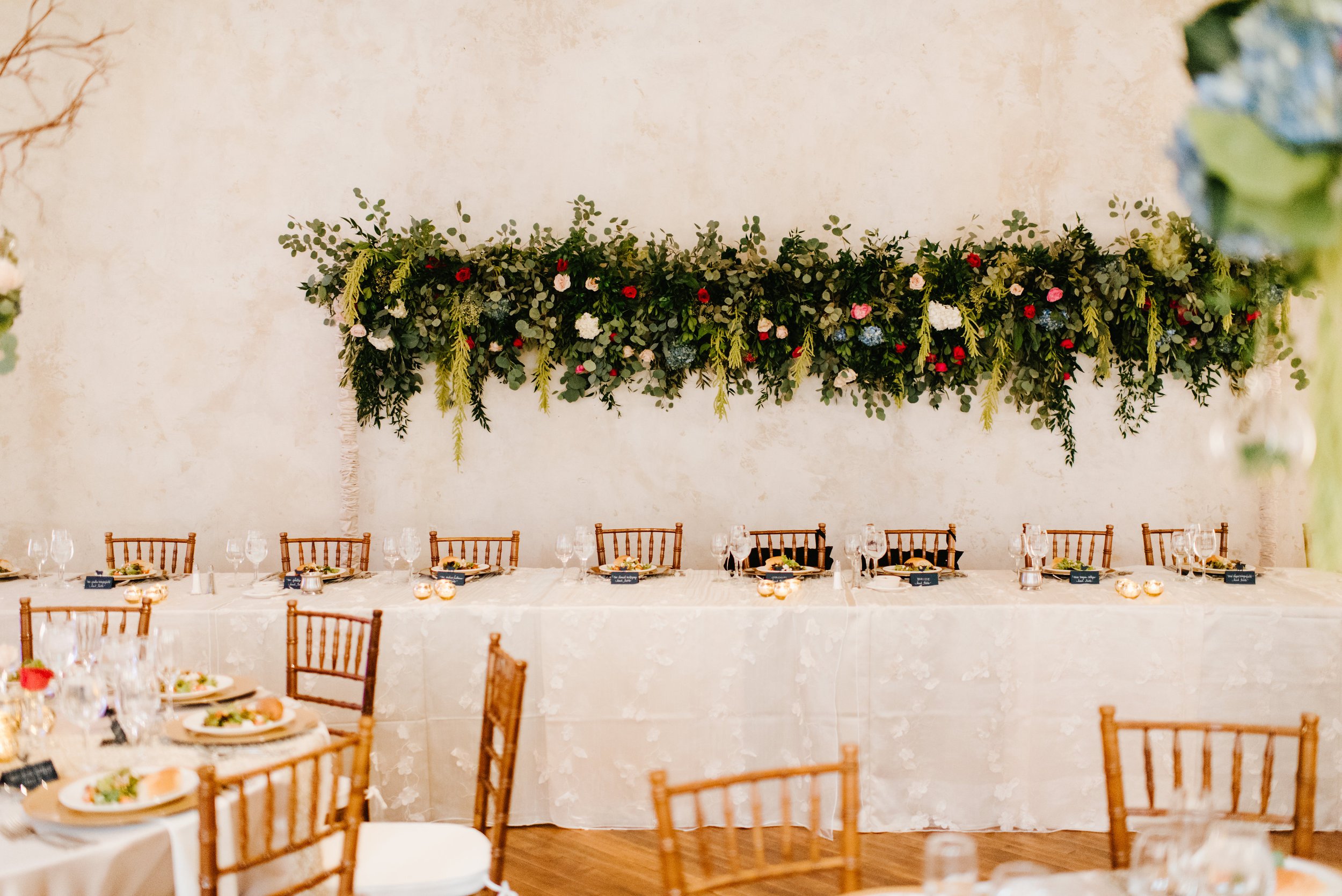 Dinner table with long hanging greenery decor and wooden chairs