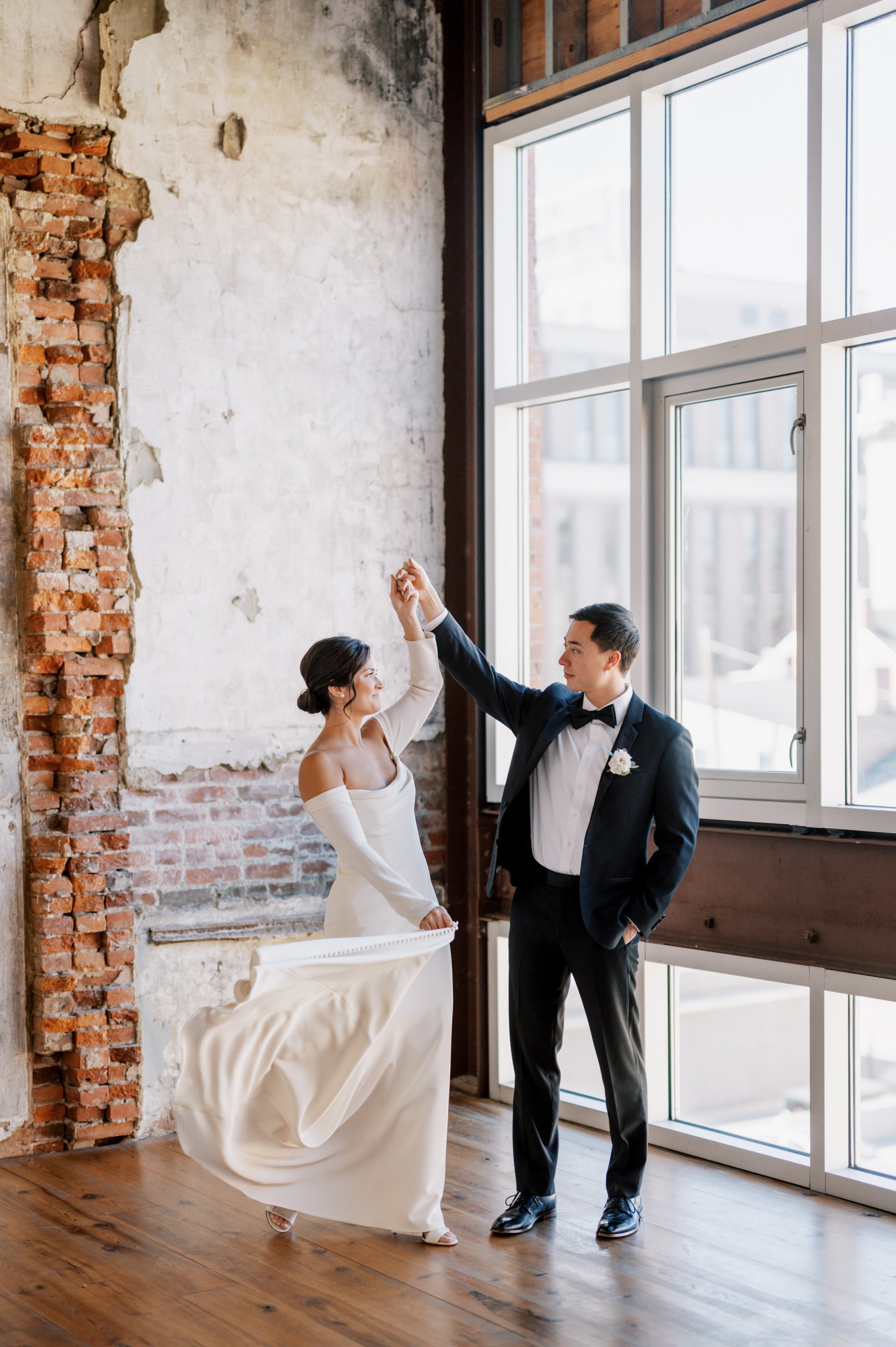 Bride groom dancing in rustic eclectic space large windows