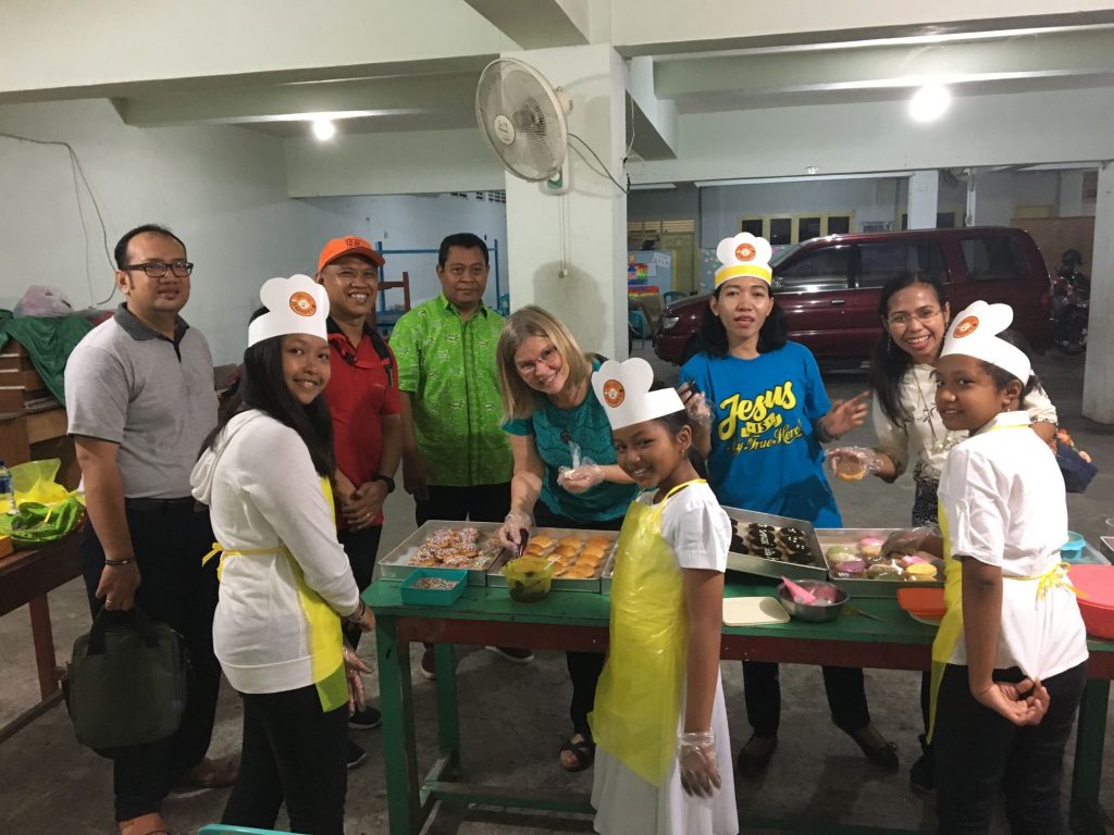 Kids and leaders making donuts. SAIN leaders Pastor Noto (red shirt) and Monica (2nd from right), GGBI President Pastor Wartono (green shirt)