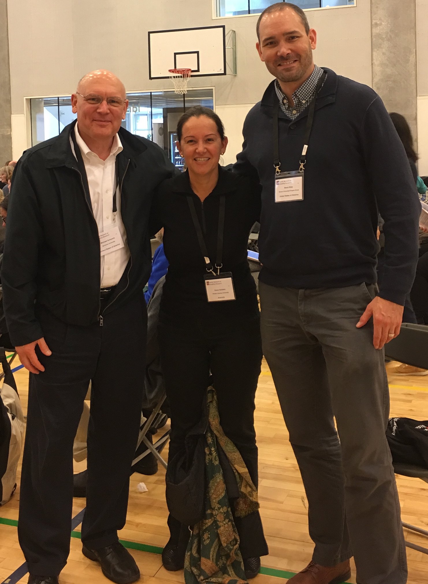 Michael Schwartz (left, black jacket and white shirt) stands with critical disability studies scholar Karen Soldatic of Western Sydney University (middle, black shirt), and Brent Elder (right, blue sweater).