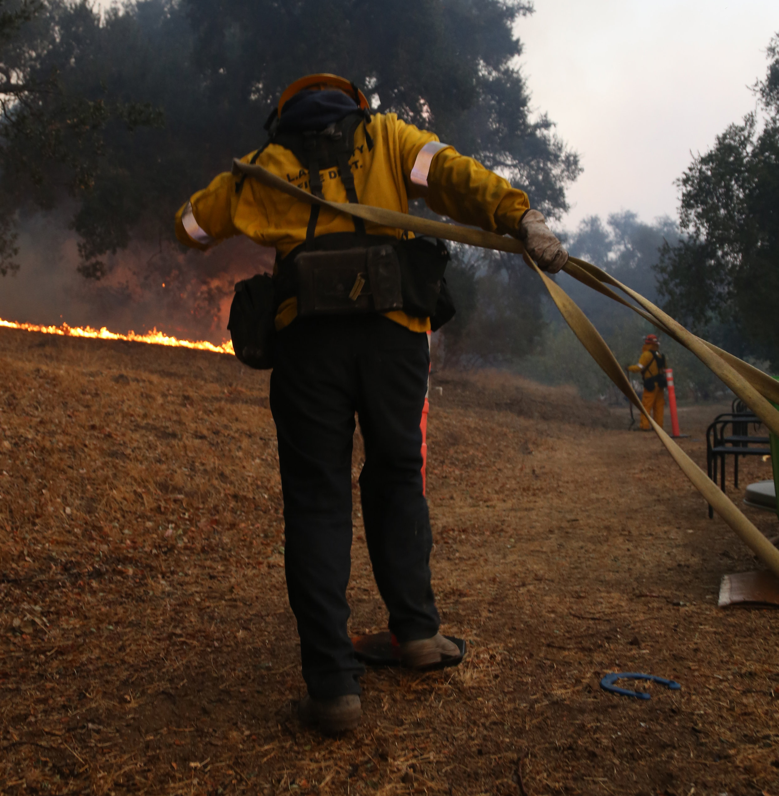 Michael Watkins Firefighters rush to lay down hose as the fire makes its way down a hill in Fillmore Calif. in the early morning hours on December 15, 2017 while battling the Thomas Fire.
