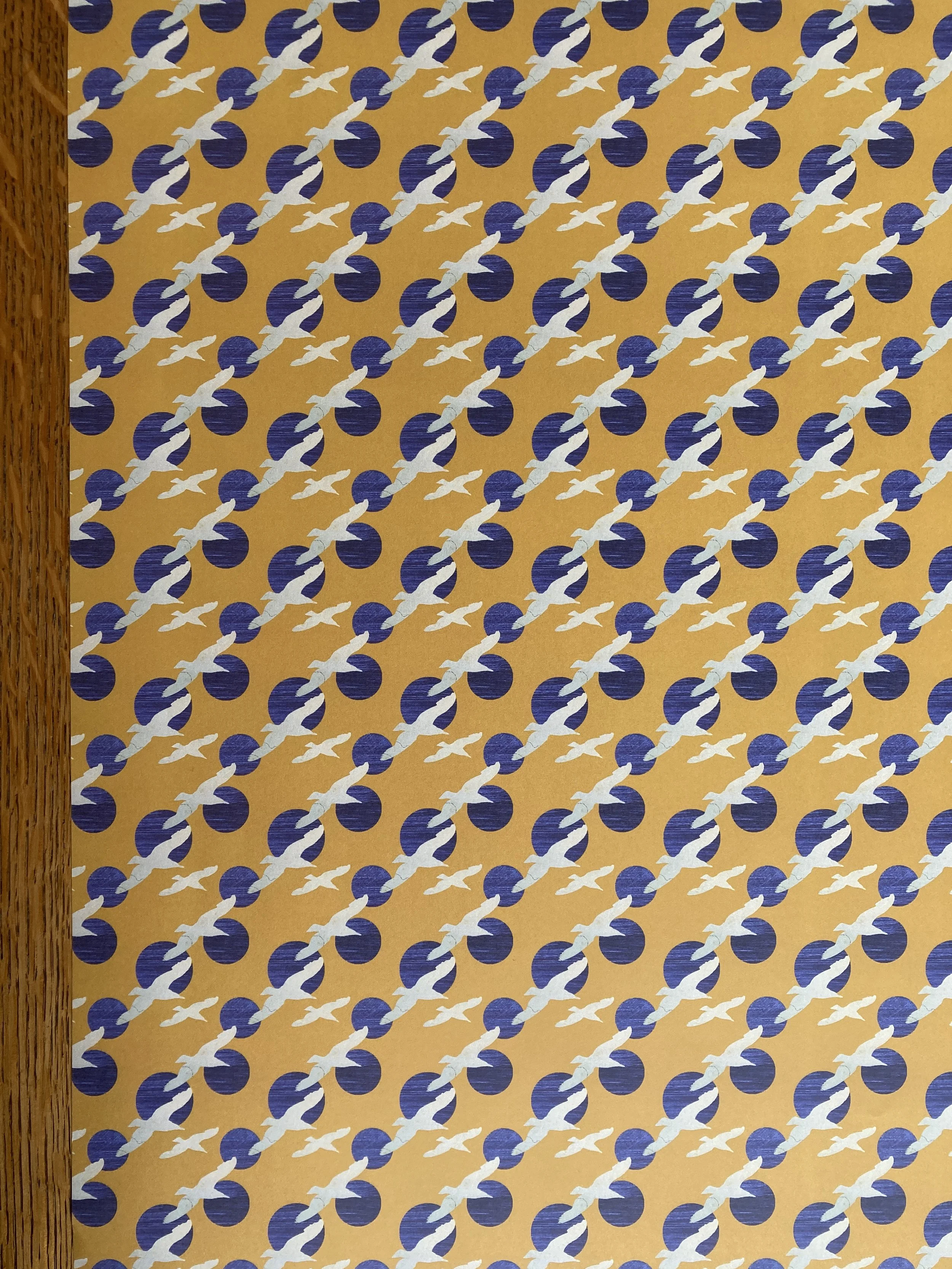 A single sheet of printed gift wrap featuring seabirds and blue circles on a yellow background