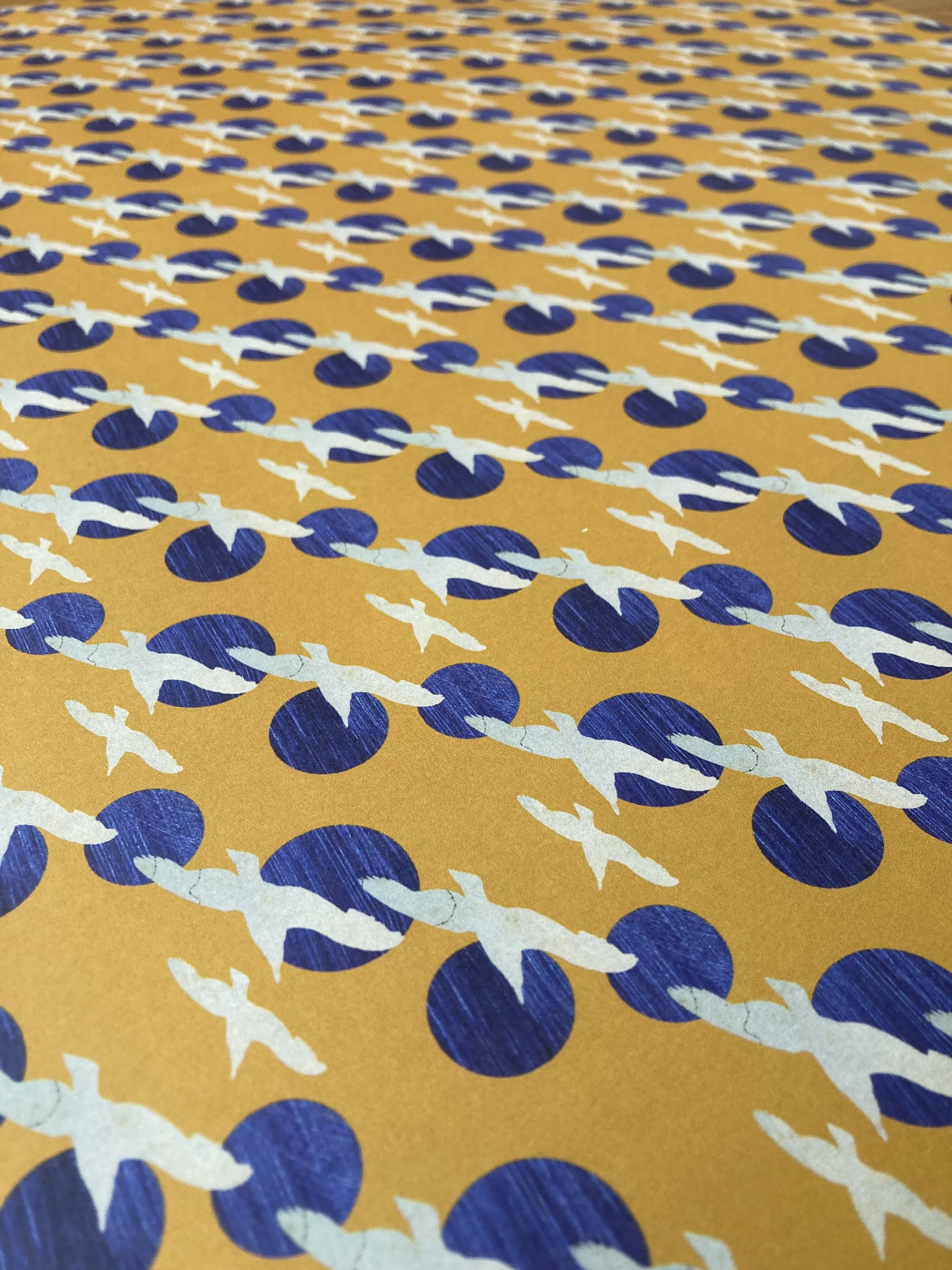 A single sheet of printed gift wrap featuring seabirds and blue circles on a yellow background