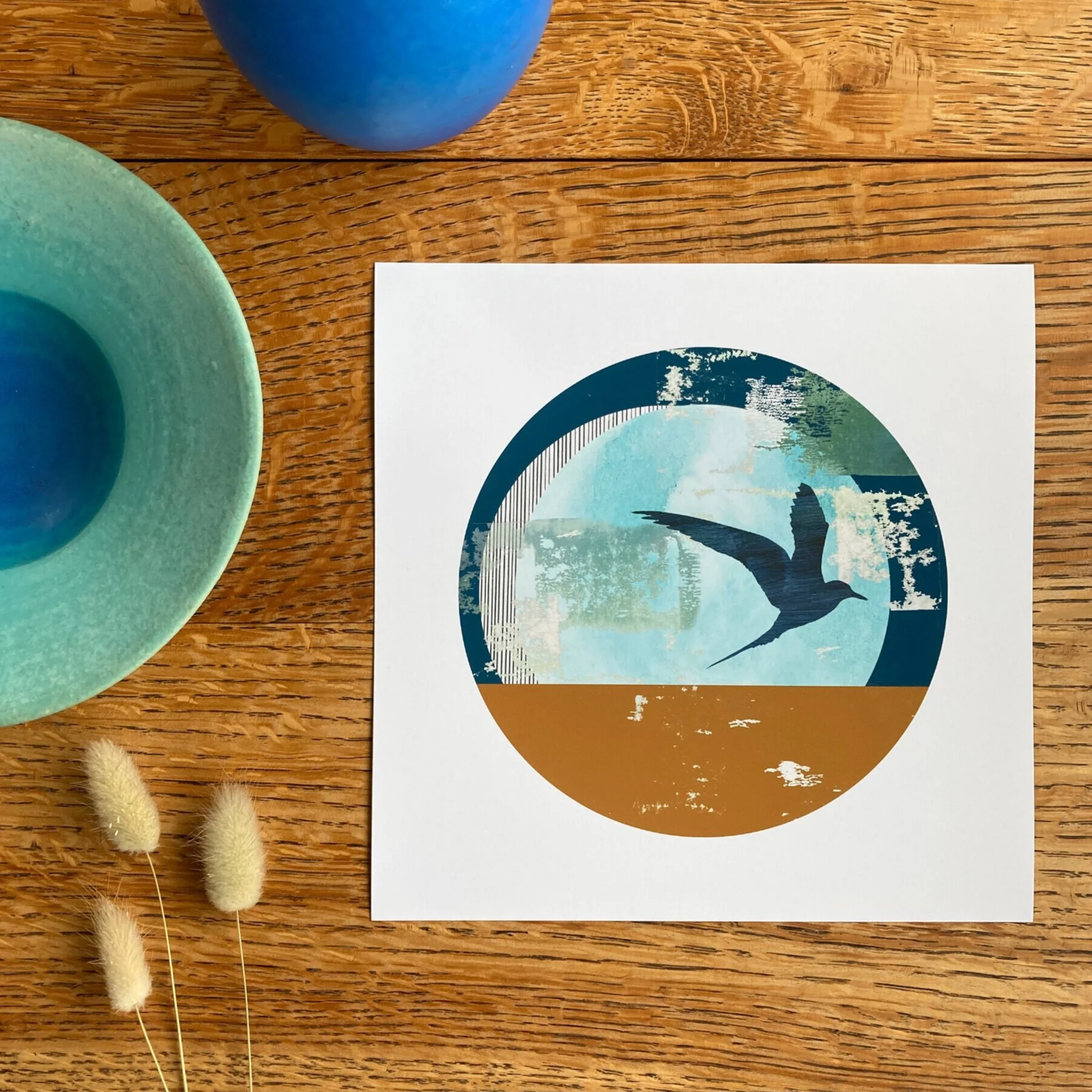 Let's Tern the Tide, an 8x8" mini fine art print of an Arctic tern with abstract shapes in blues and ochre. The design has a circular aperture with white border