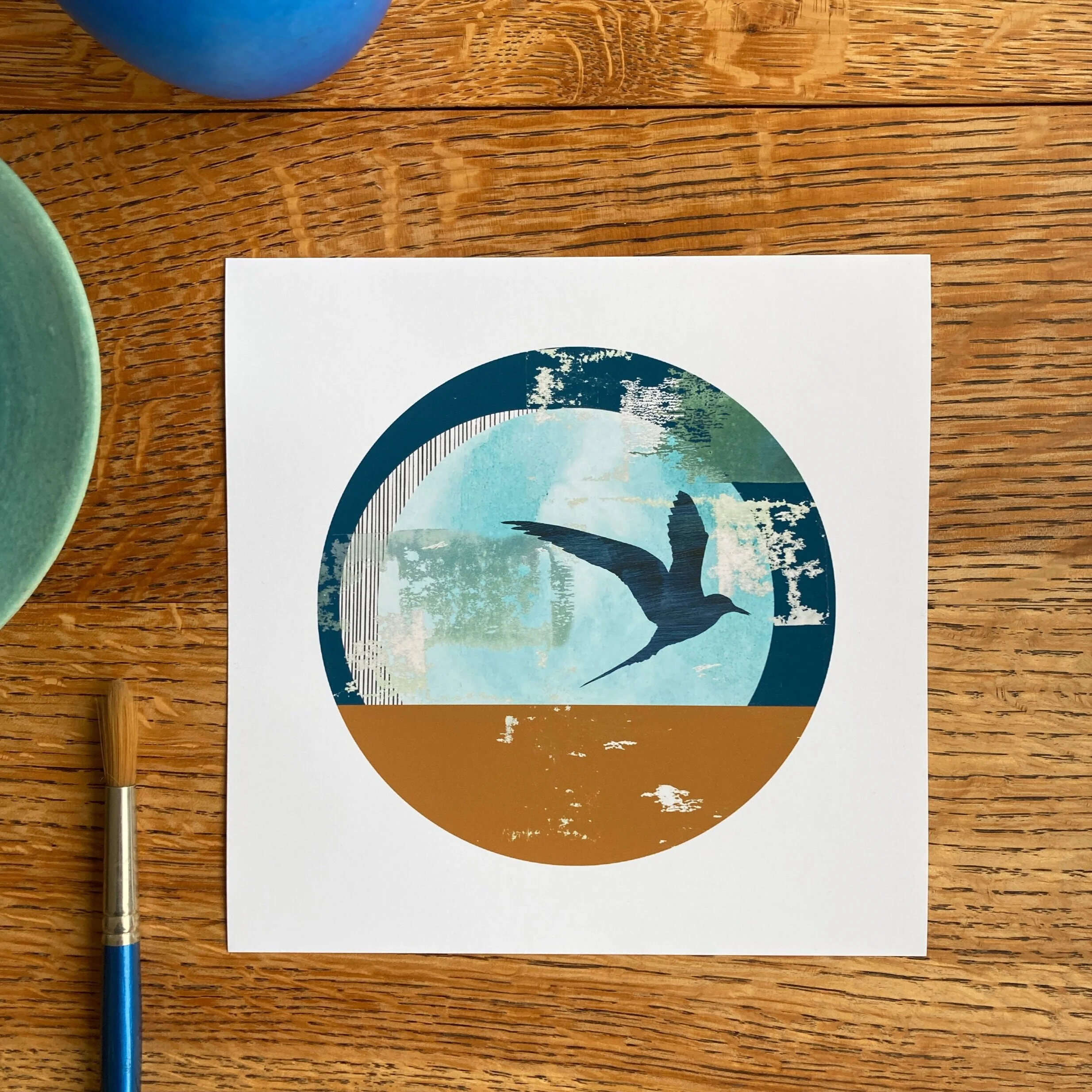 Let's Tern the Tide, an 8x8" mini fine art print of an Arctic tern with abstract shapes in blues and ochre. The design has a circular aperture with white border