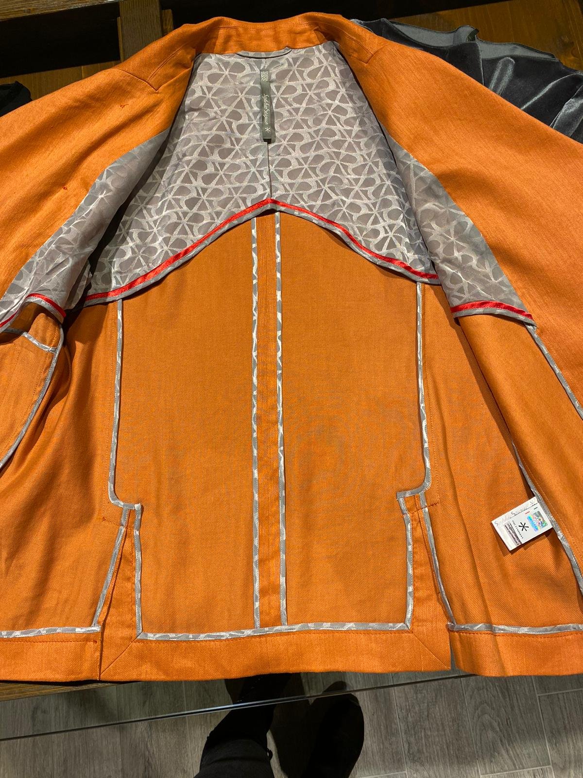Giacca asimmetrica in gabardina misto canapa e cotone stretch arancio e mezza fodera misto cupro e cotone logata grigia