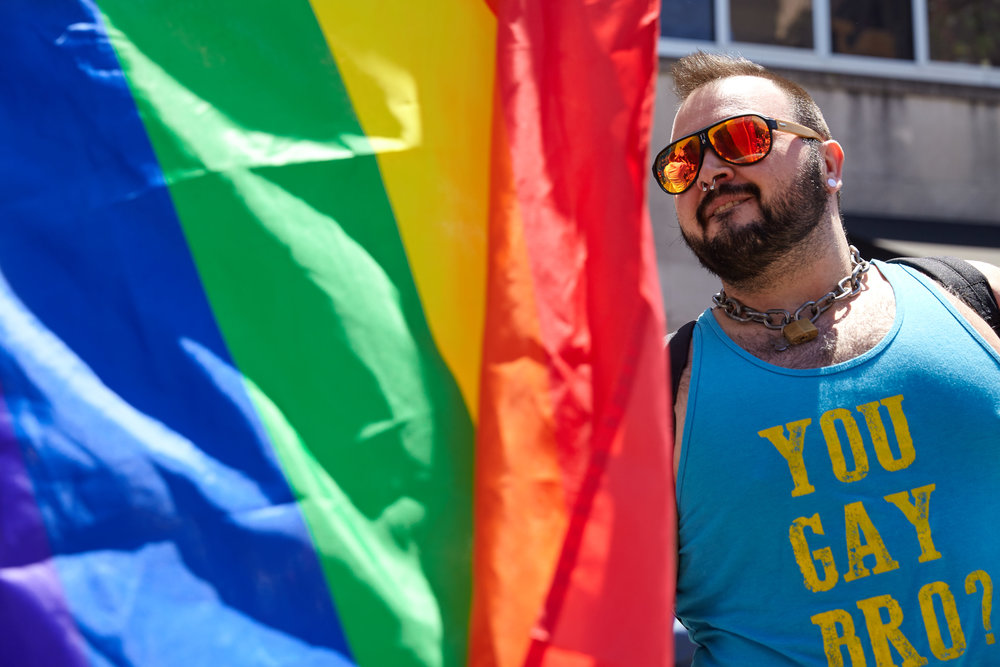 A Big Gay Dance Party attendee dances next to a rainbow flag.