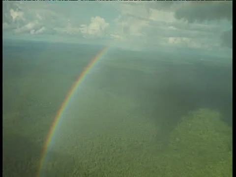 High in the sky, a rainbow arches over the amazon