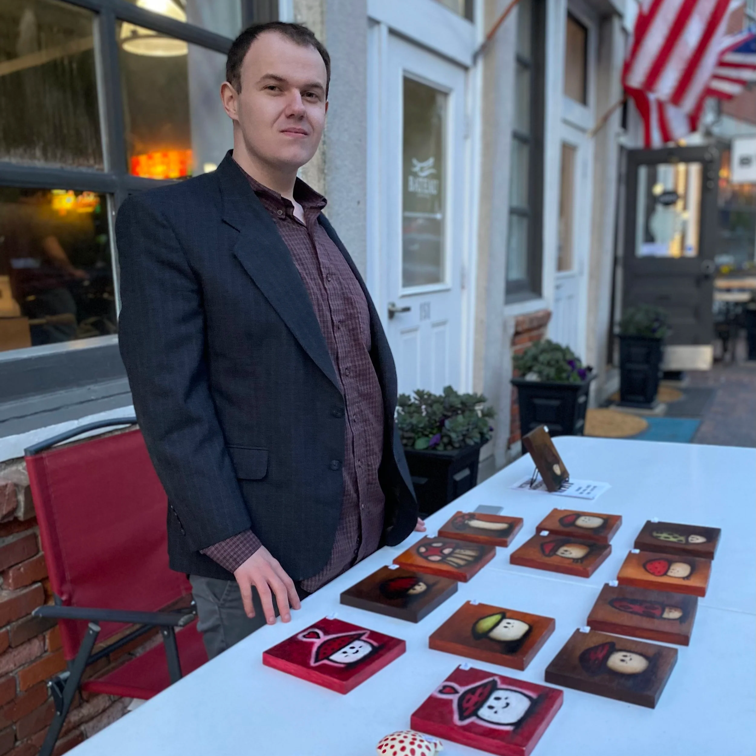 Artist Donald L. Patten standing beside a table displaying a selection of his small-scale artworks.