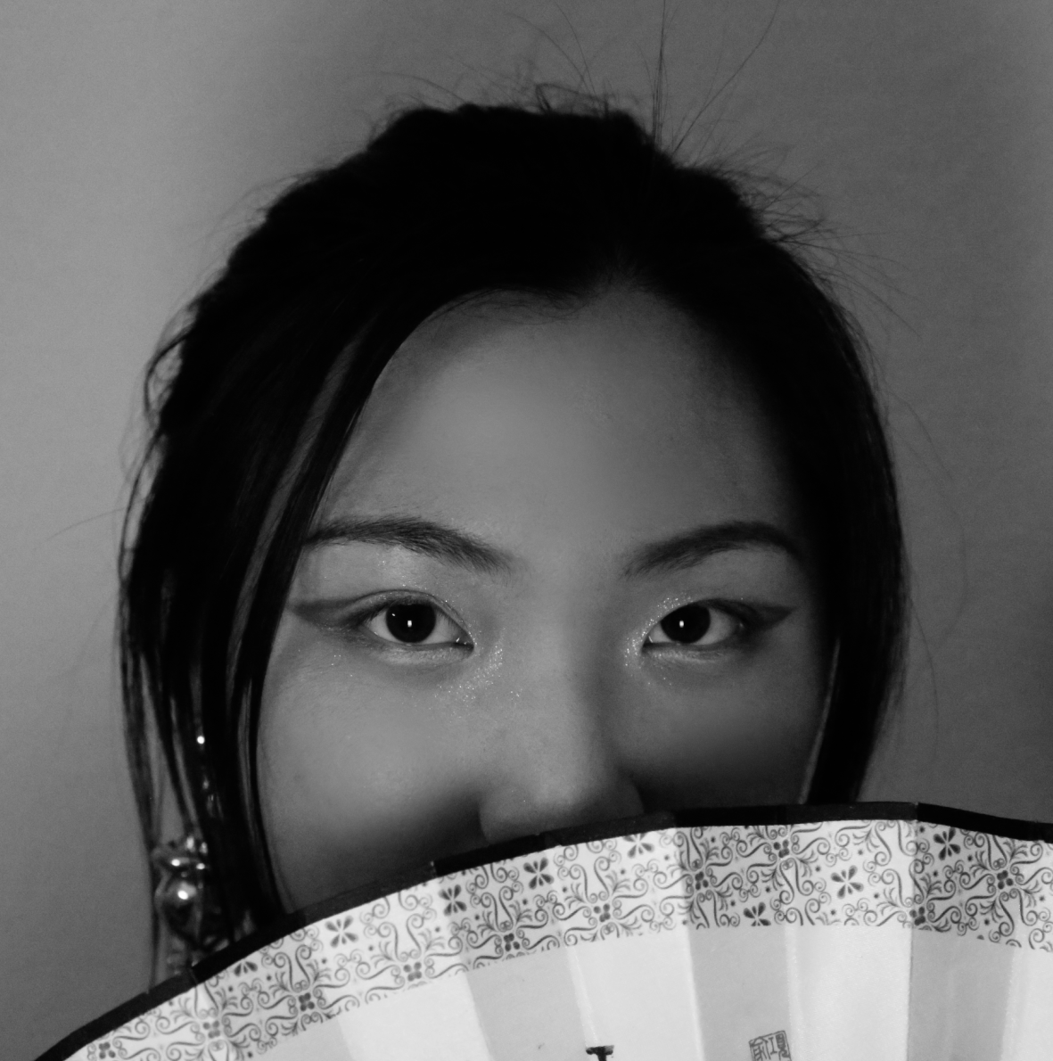 A black and white photo of the poet with their face partially obscured by a fan.
