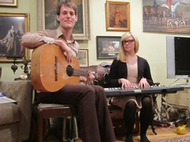 Adult piano student Ryan practicing with teacher Andrew on guitar and electronic keyboard in Ryan's apartment.