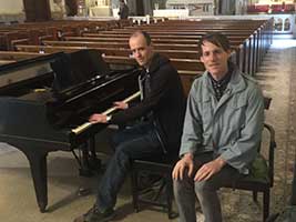 Adult piano student Ken and teacher Andrew seated at a grand piano in a historic Brooklyn church.