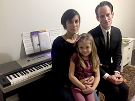 Mother and daughter piano students Minal and Nishka sitting with teacher Andrew at a digital piano.
