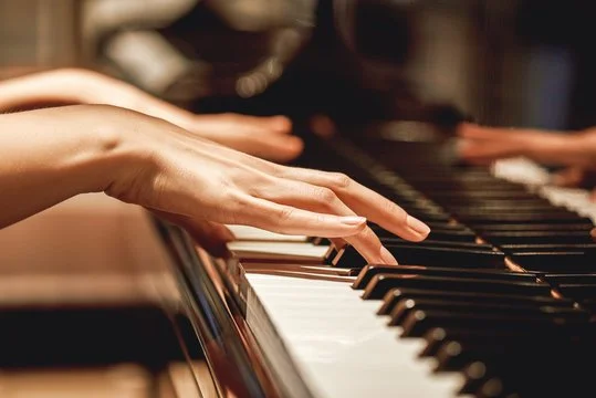 Close-up of piano player’s hands on the keyboard during a lesson.