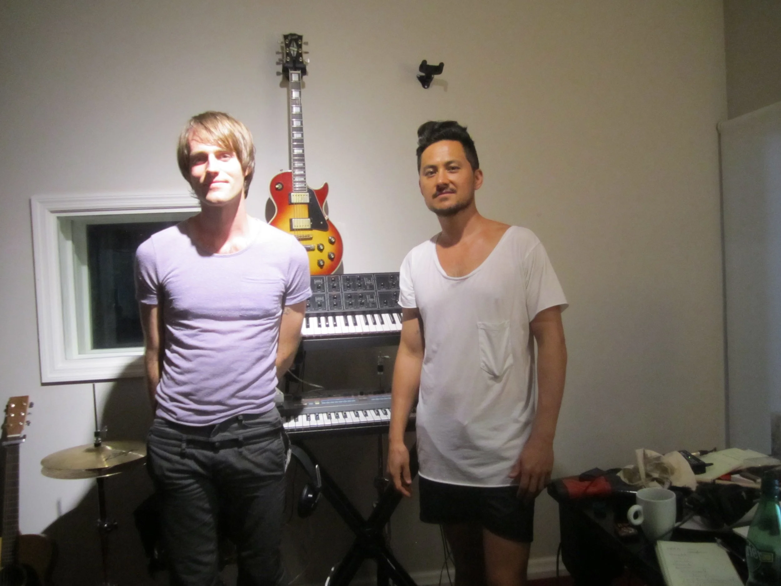 Two piano teachers posing together with instruments in a Brooklyn studio.