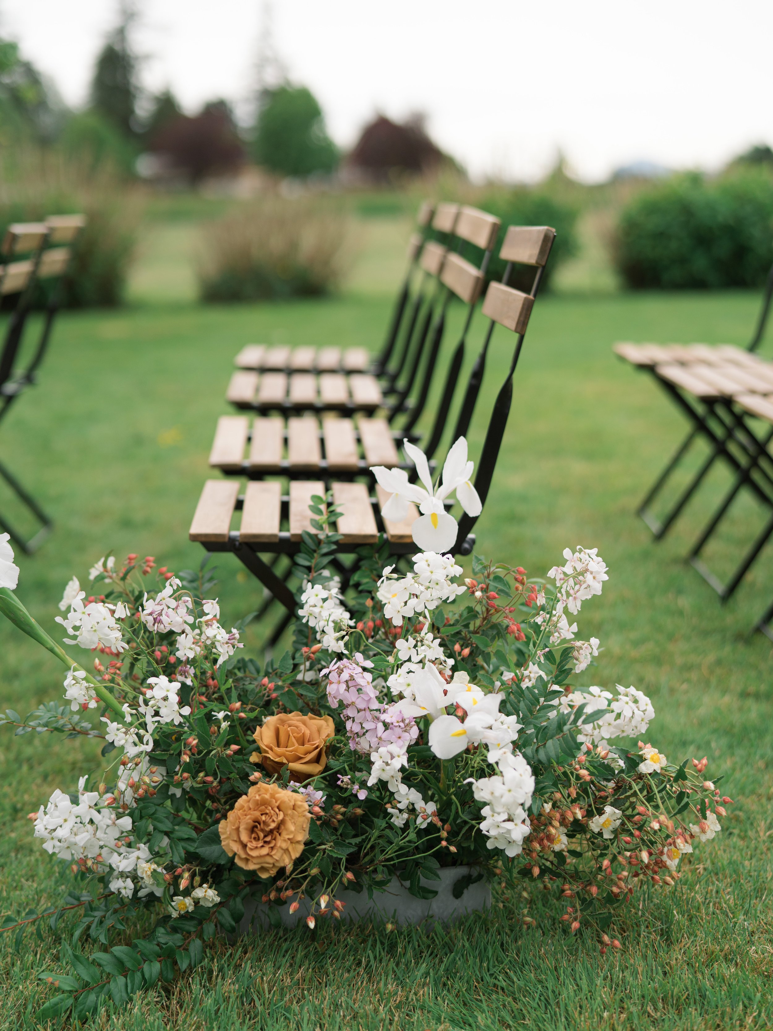pacific-engagements-tetiana-photography-leah-erickson-floral-santucci-farm-wedding-ceremony-vintage-farm-chairs-with-white-flower-arrangements-down-ceremony-aisle-for-spring-wedding