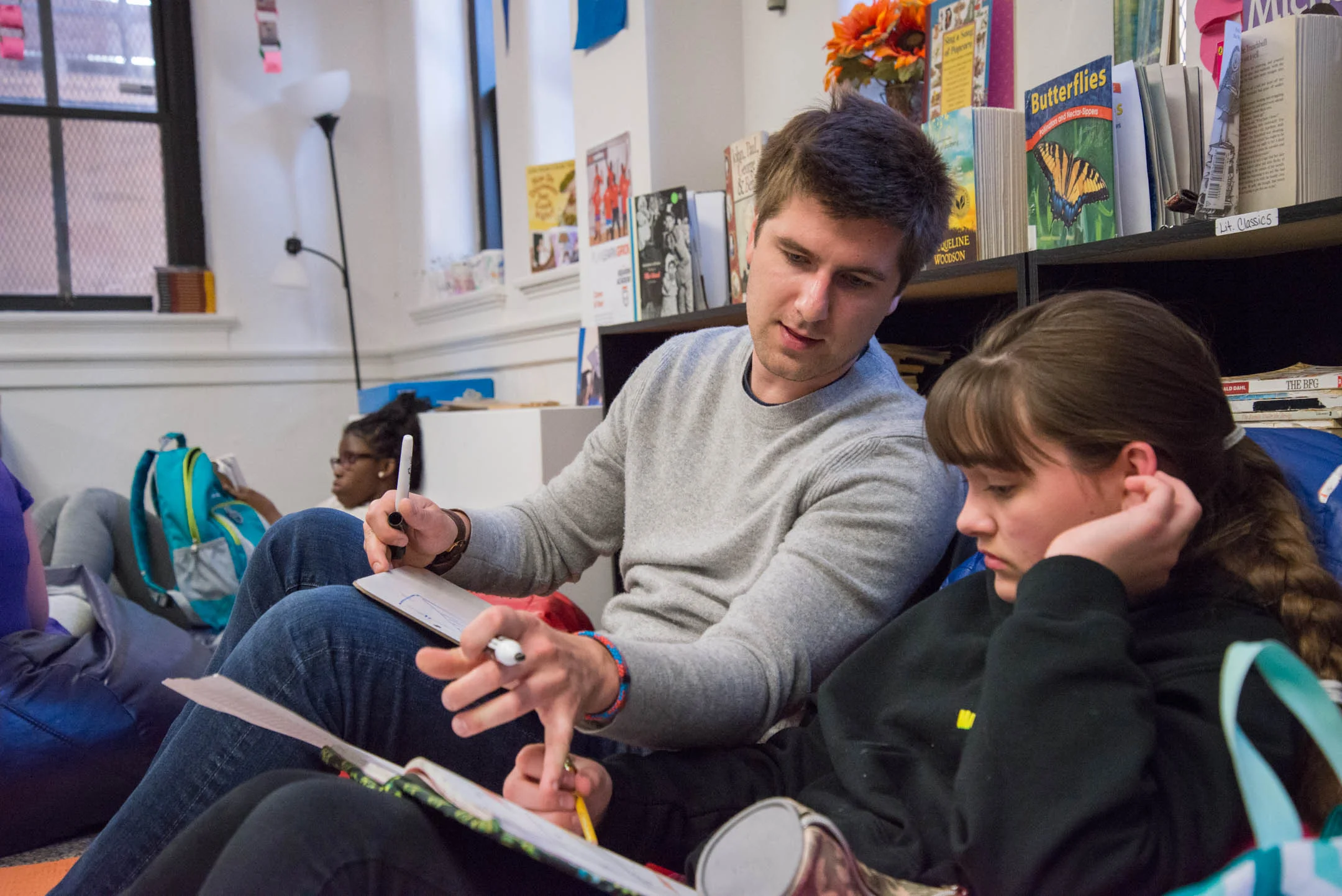Austin Schiff, executive director of the Cincinnati Squash Academy, helps Reese Clary with math work at the Cincinnati Squash Academy. The program incorporates an emphasis on education in addition to athletics.